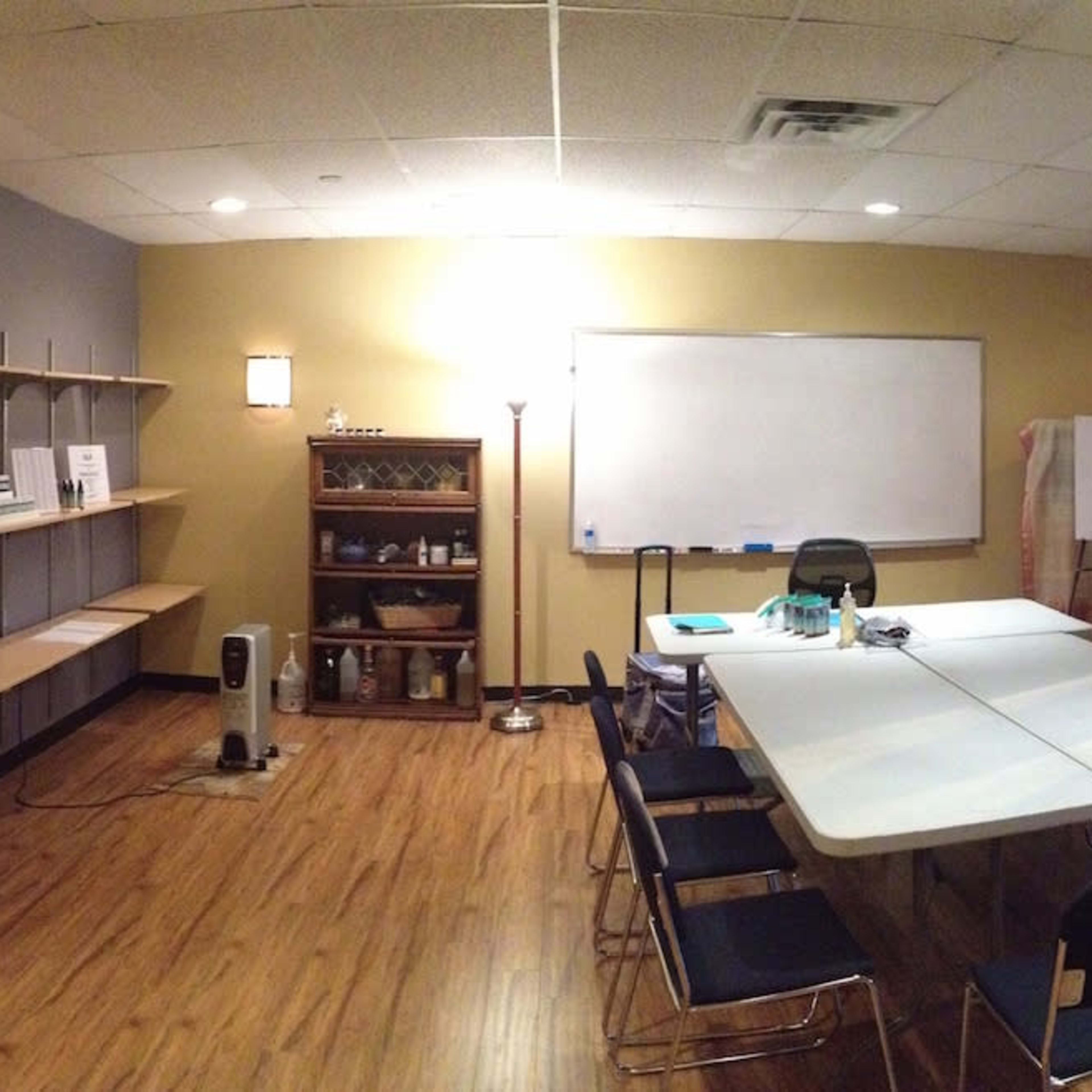 A spacious, well-lit room with a reception area, a large meeting table, and several seating stations arranged along the windows.