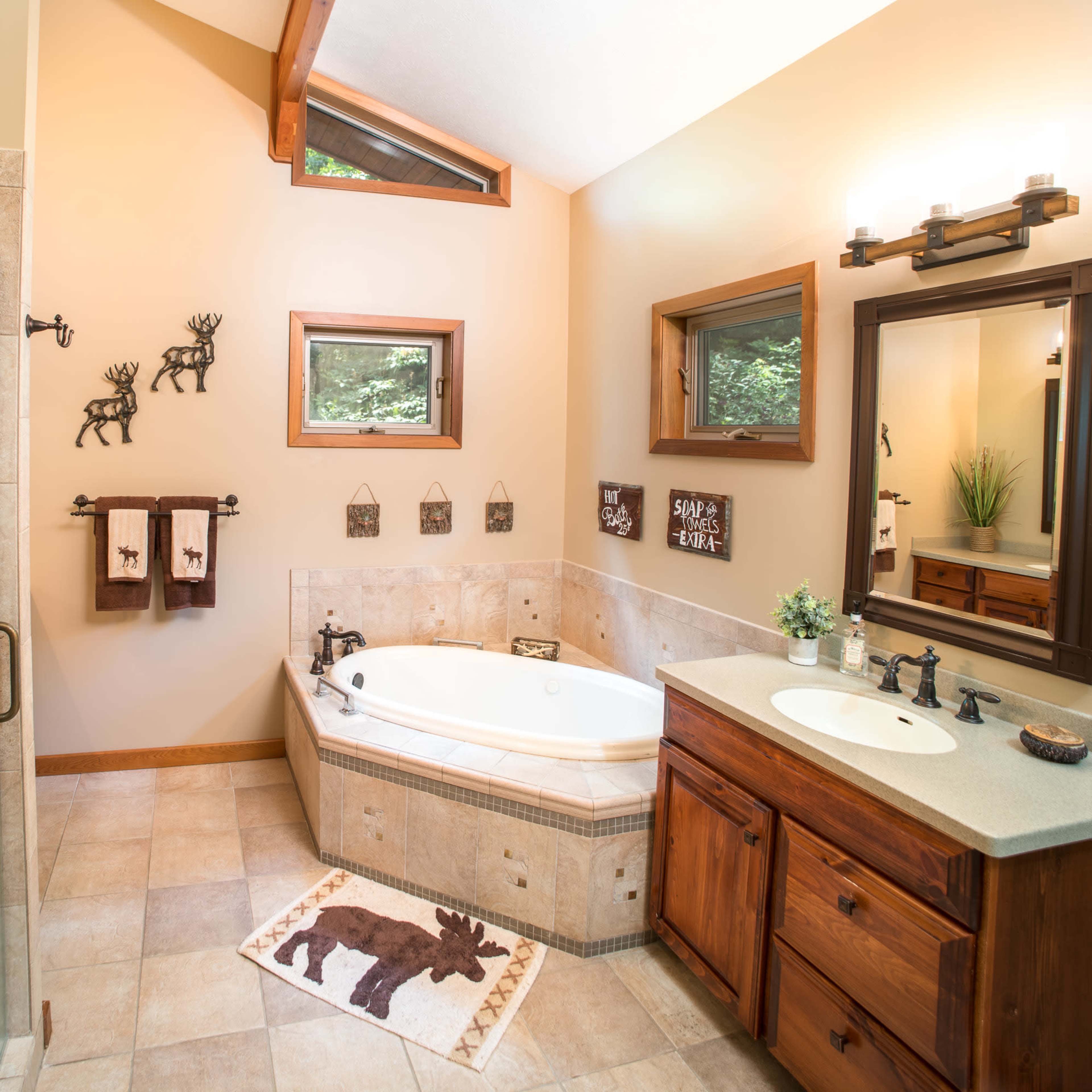 The bathroom features a glass shower, a whirlpool tub, wooden cabinetry, and decorative moose-themed accessories.