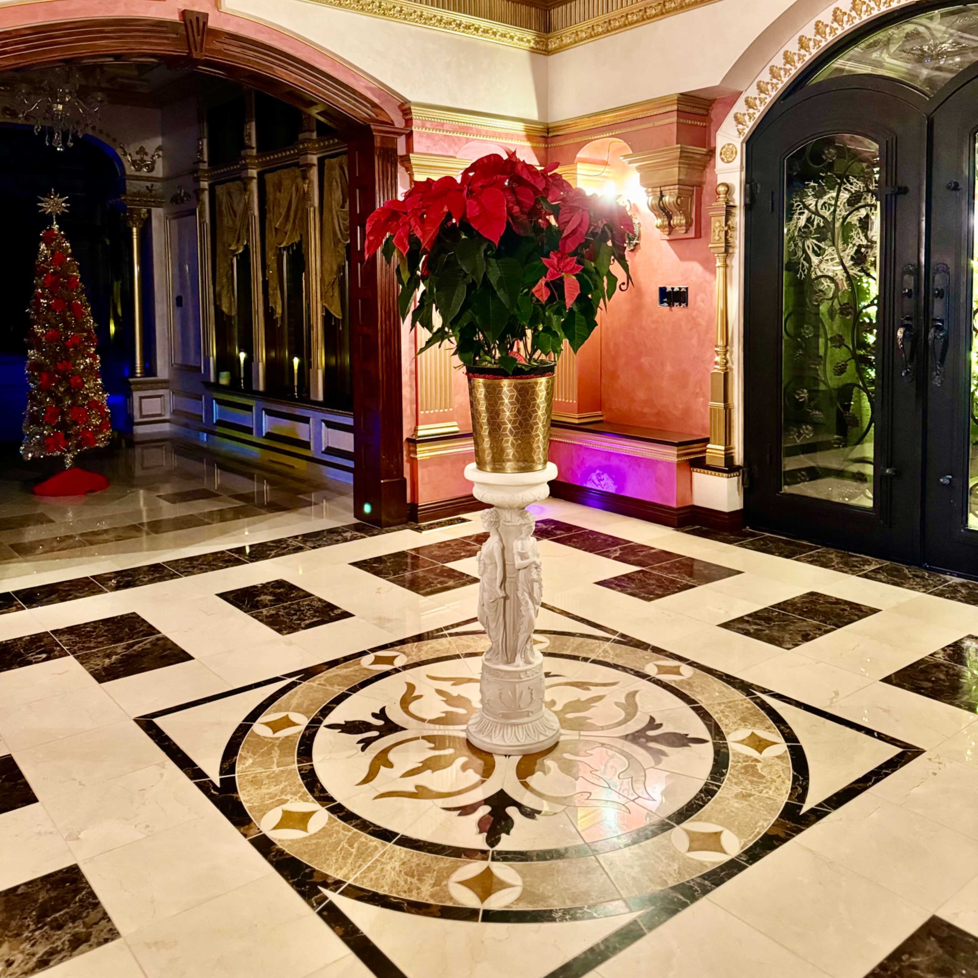 An elegantly decorated entryway featuring a central floral arrangement and ornate ceiling details.