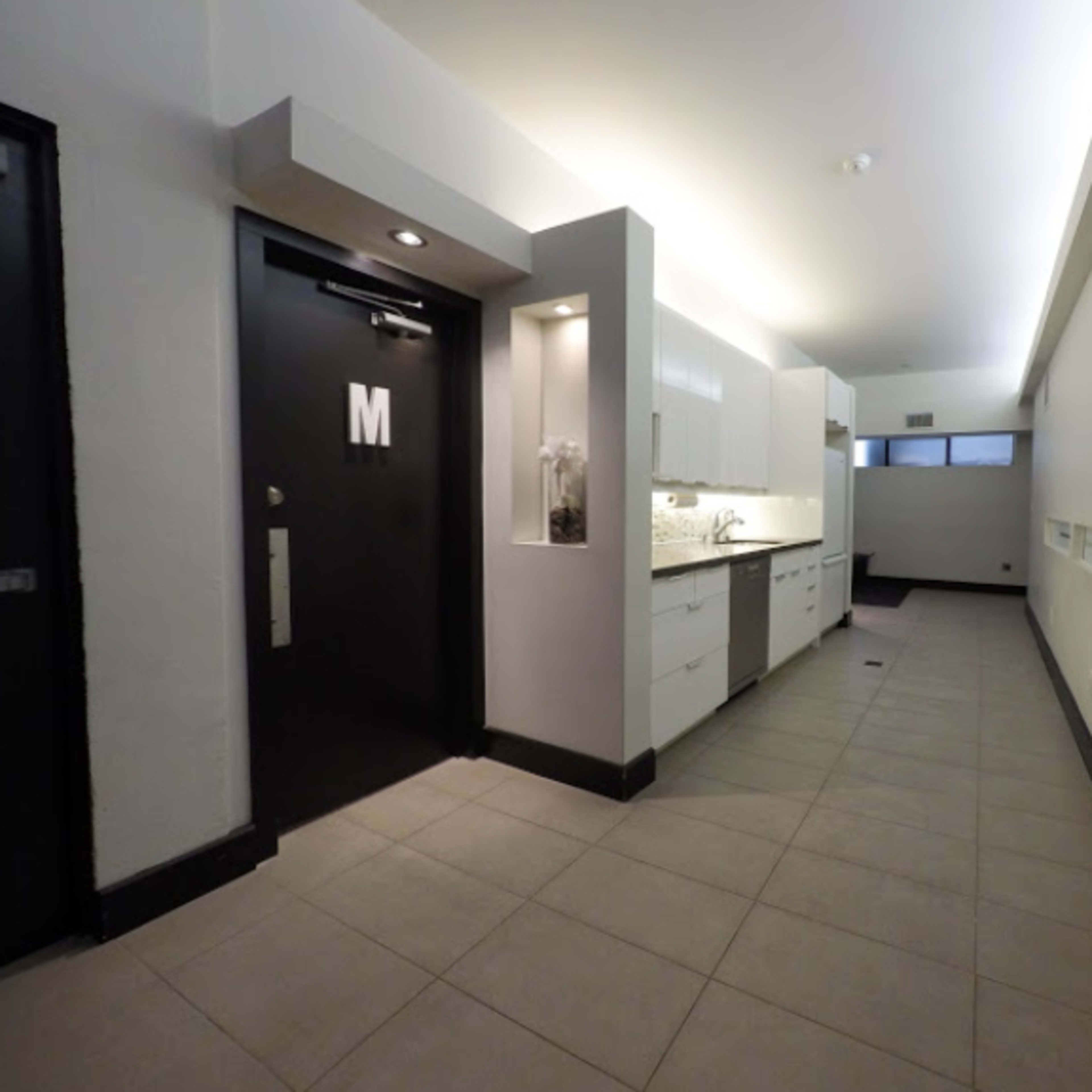 A narrow hallway with a kitchen area on the left and a door labeled "M" on the right.