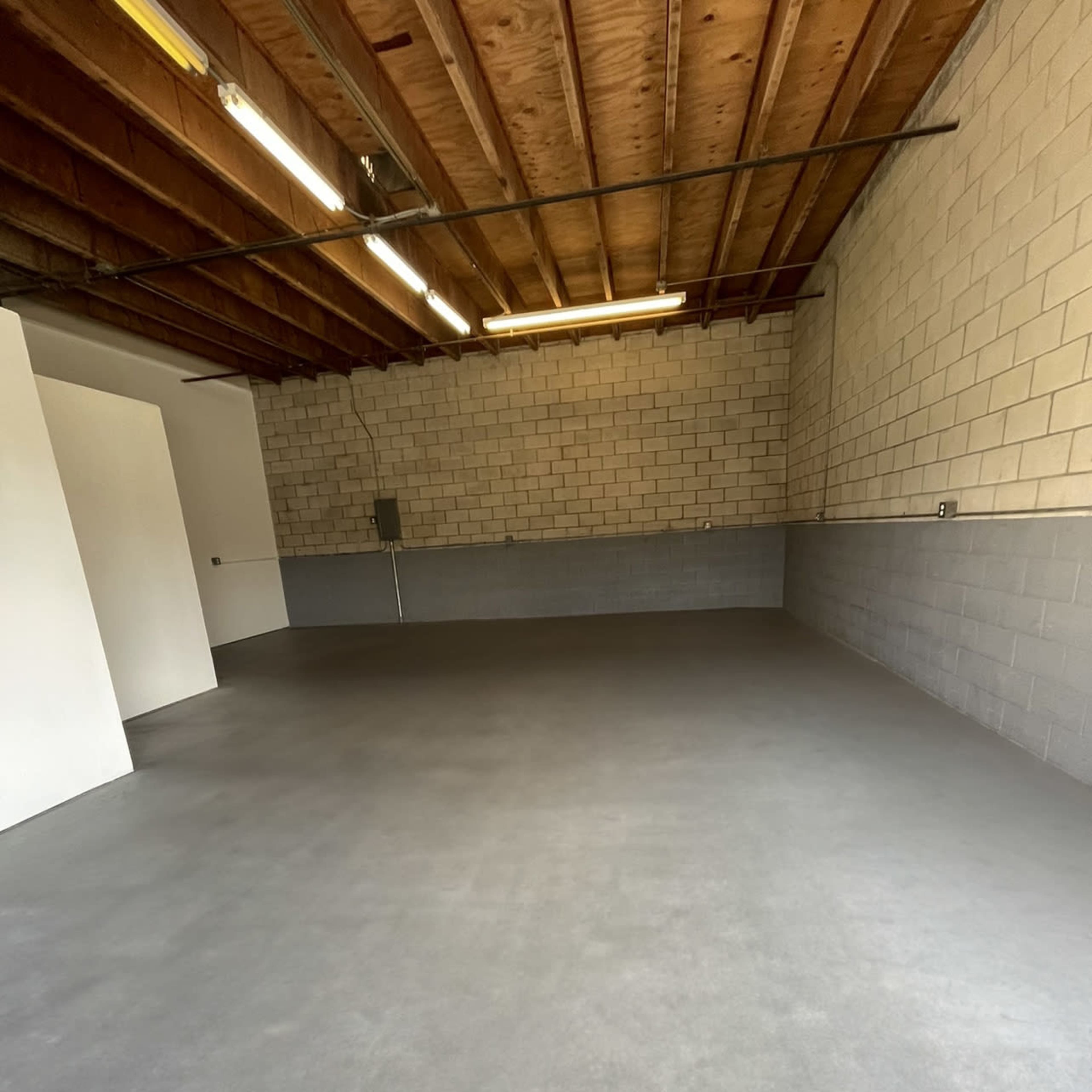 A spacious, empty garage with a concrete floor and cinder block walls.