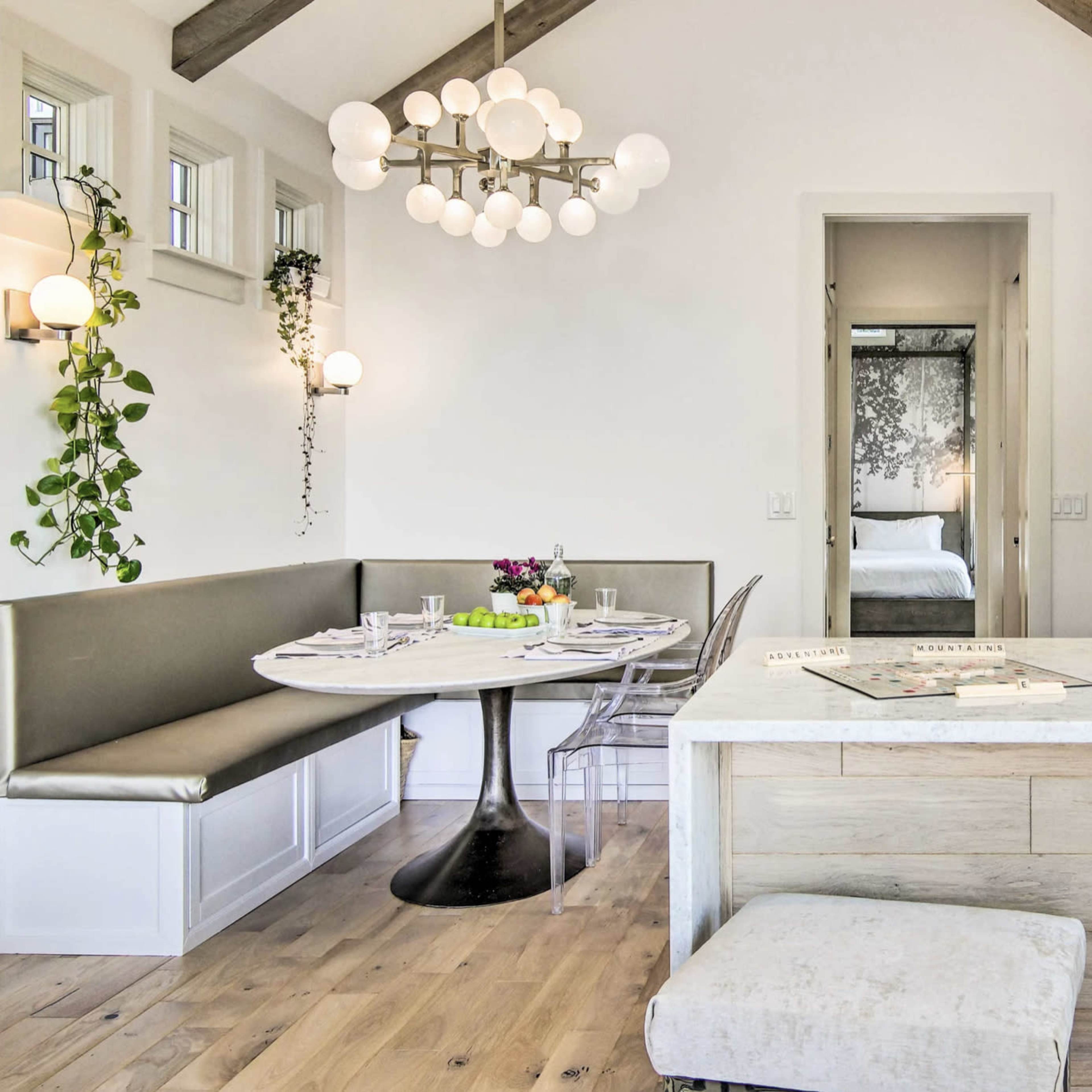 A modern kitchen and dining area feature a circular table with a built-in bench and an island with a marble countertop.