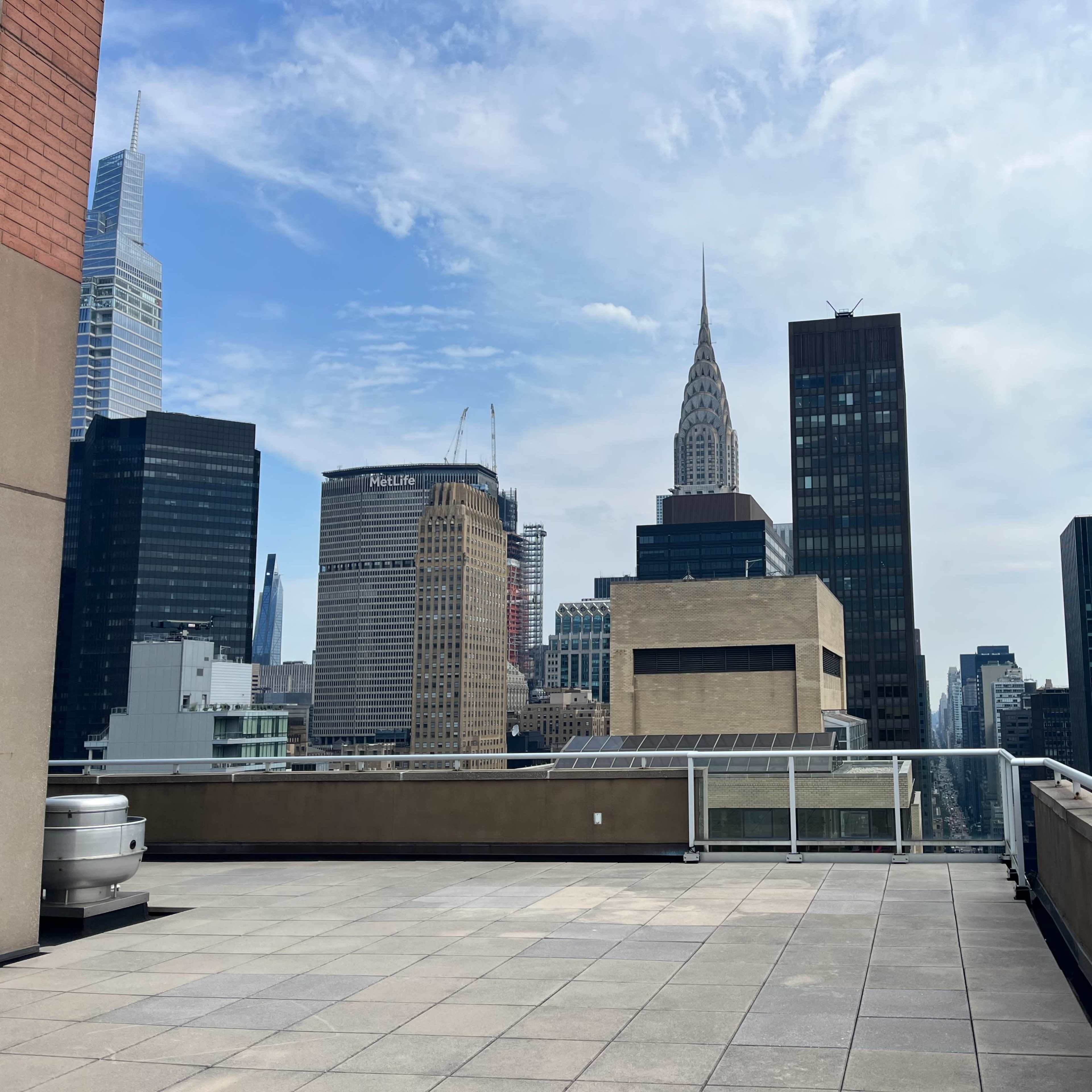 A rooftop view of skyscrapers in New York City, featuring the iconic Chrysler Building in the background.