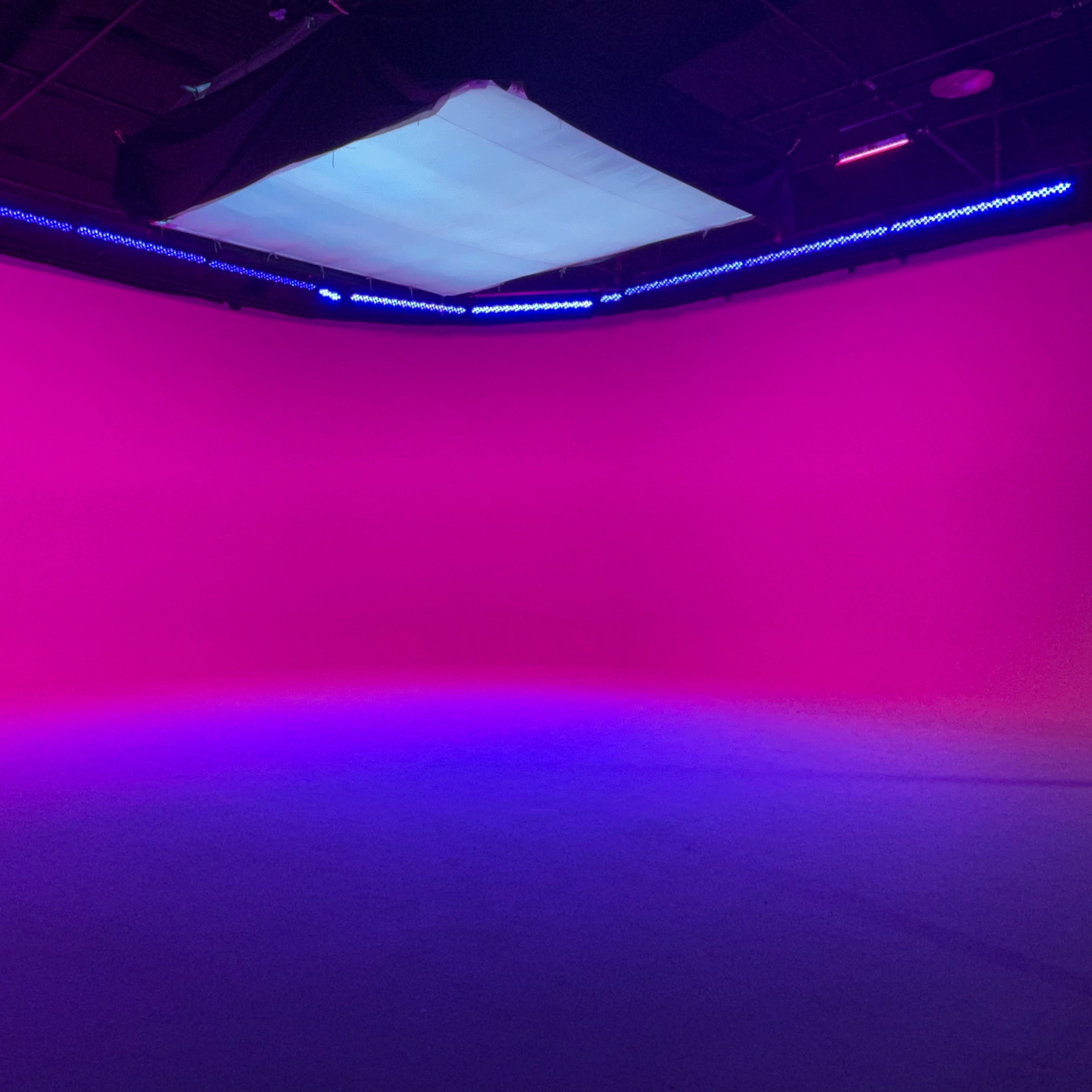 A studio space with a gradient pink to purple background and overhead lighting.