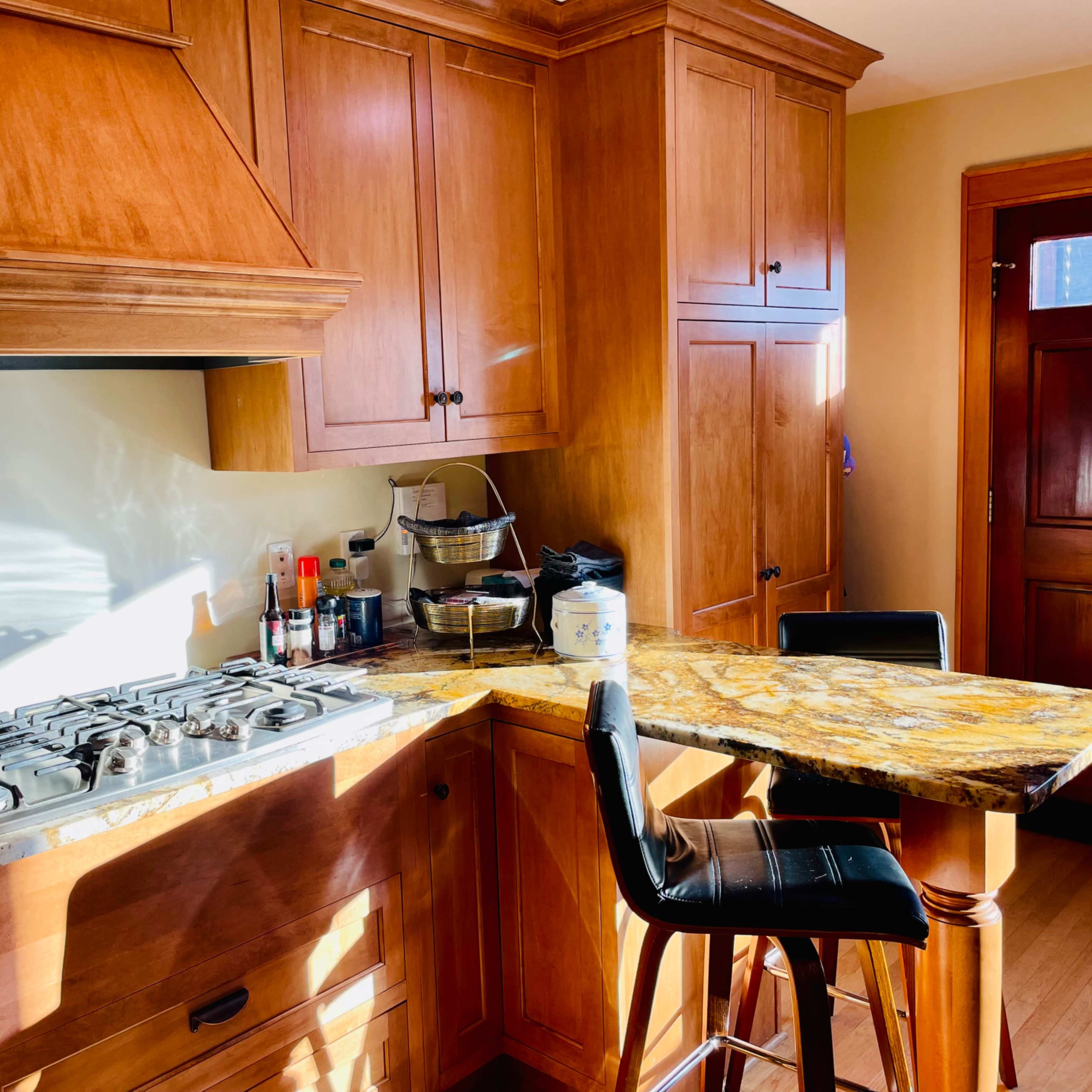 A modern kitchen features wooden cabinetry, a gas stove, and a granite countertop with a bar-height seating area.