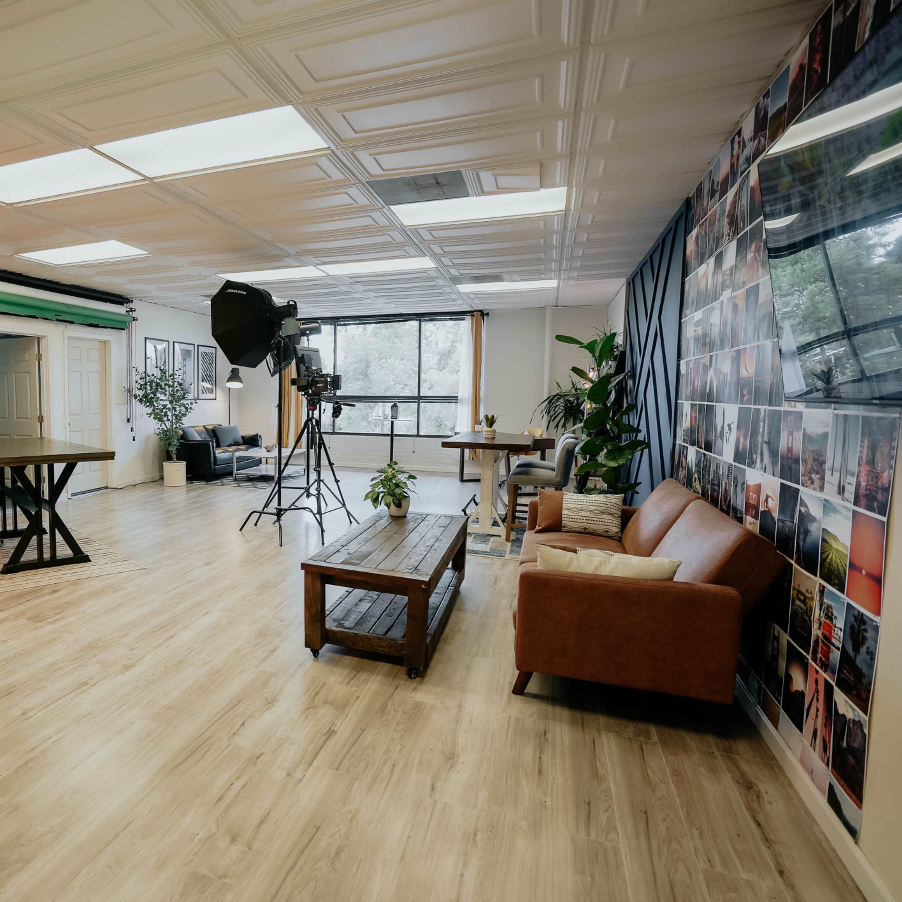 A modern studio space with a seating area, kitchenette, and backdrops for photography or filming.