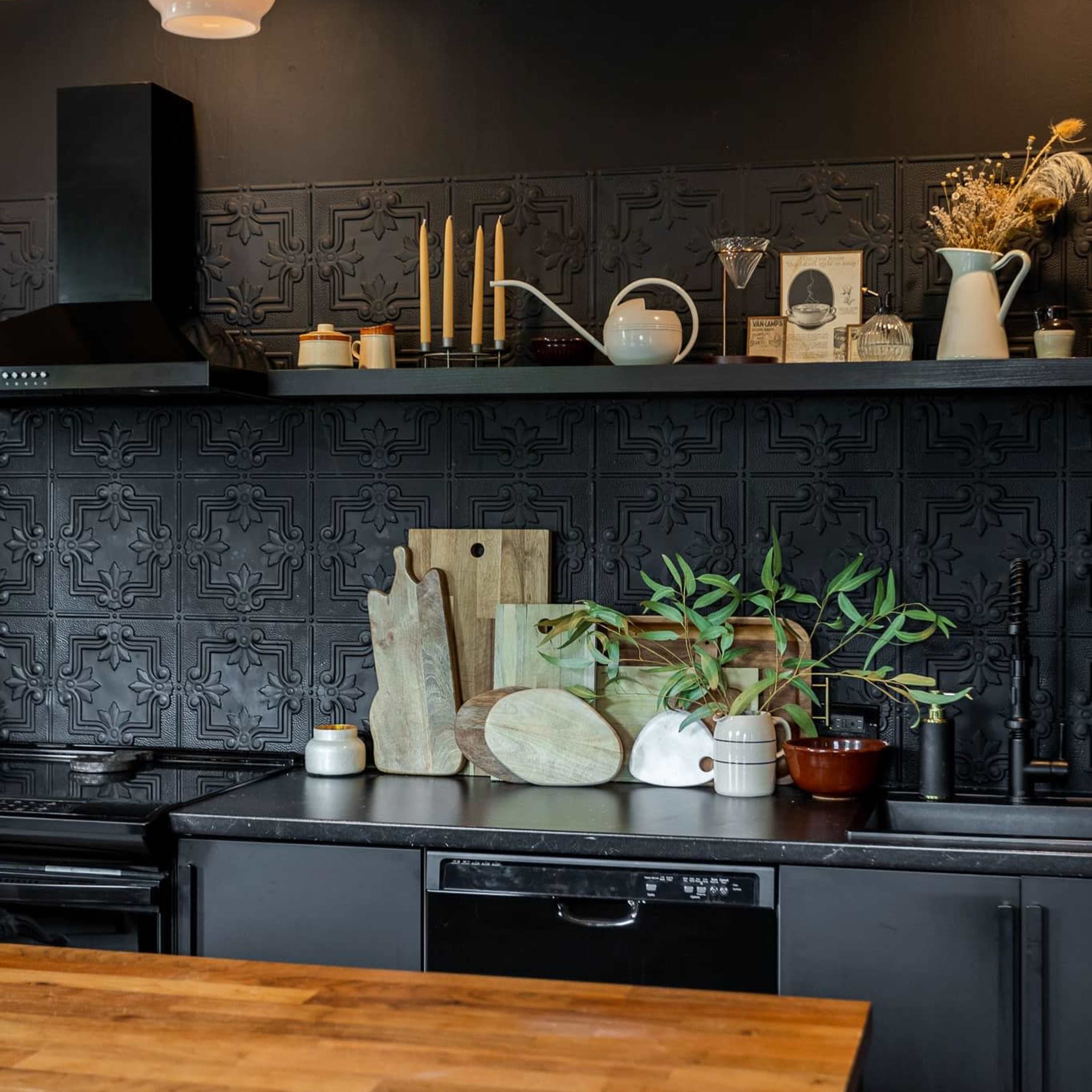 A modern kitchen featuring a black tiled backsplash, wooden cutting boards, various kitchenware, and a wooden countertop.