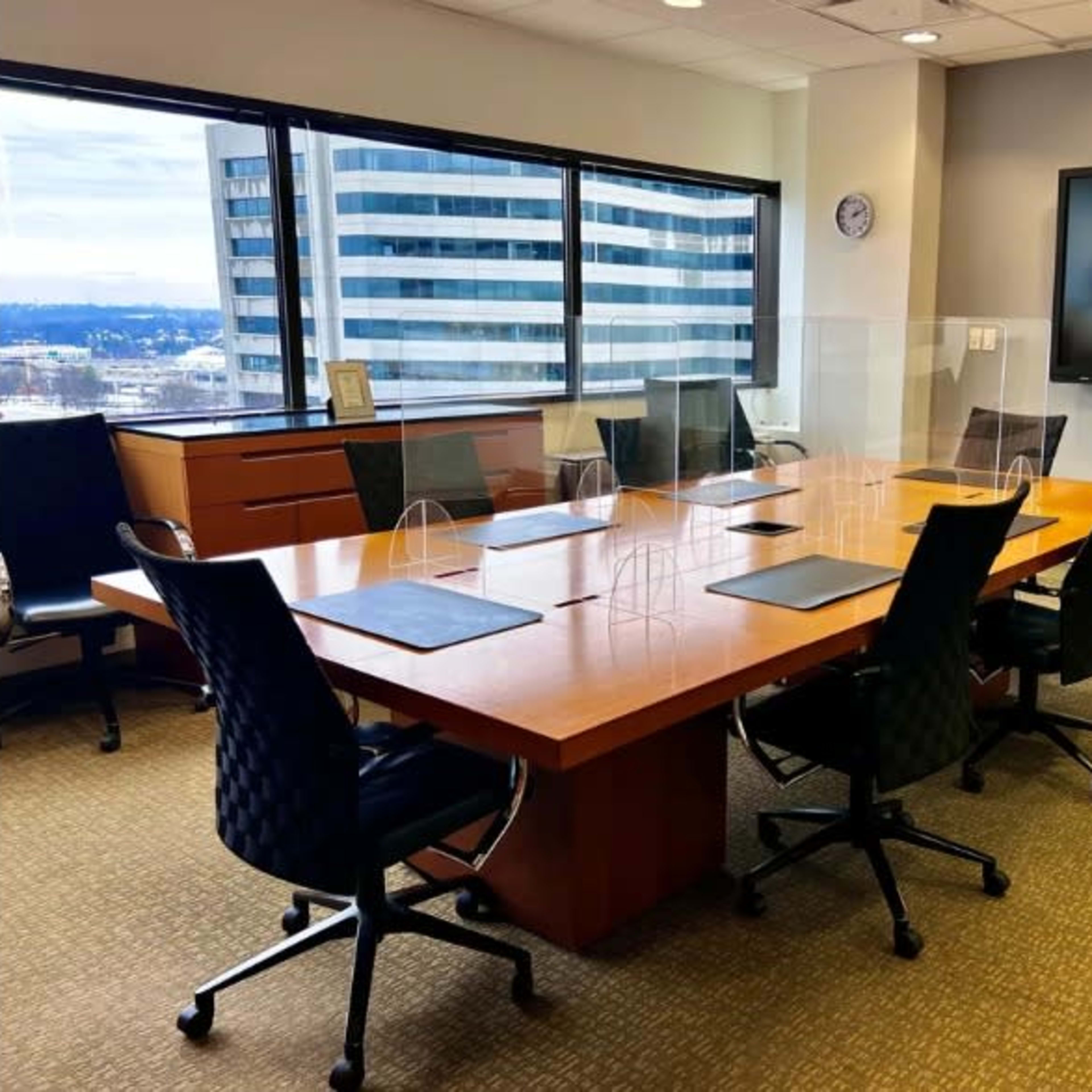 A large conference room features a rectangular wooden table surrounded by black chairs and a wall-mounted television.