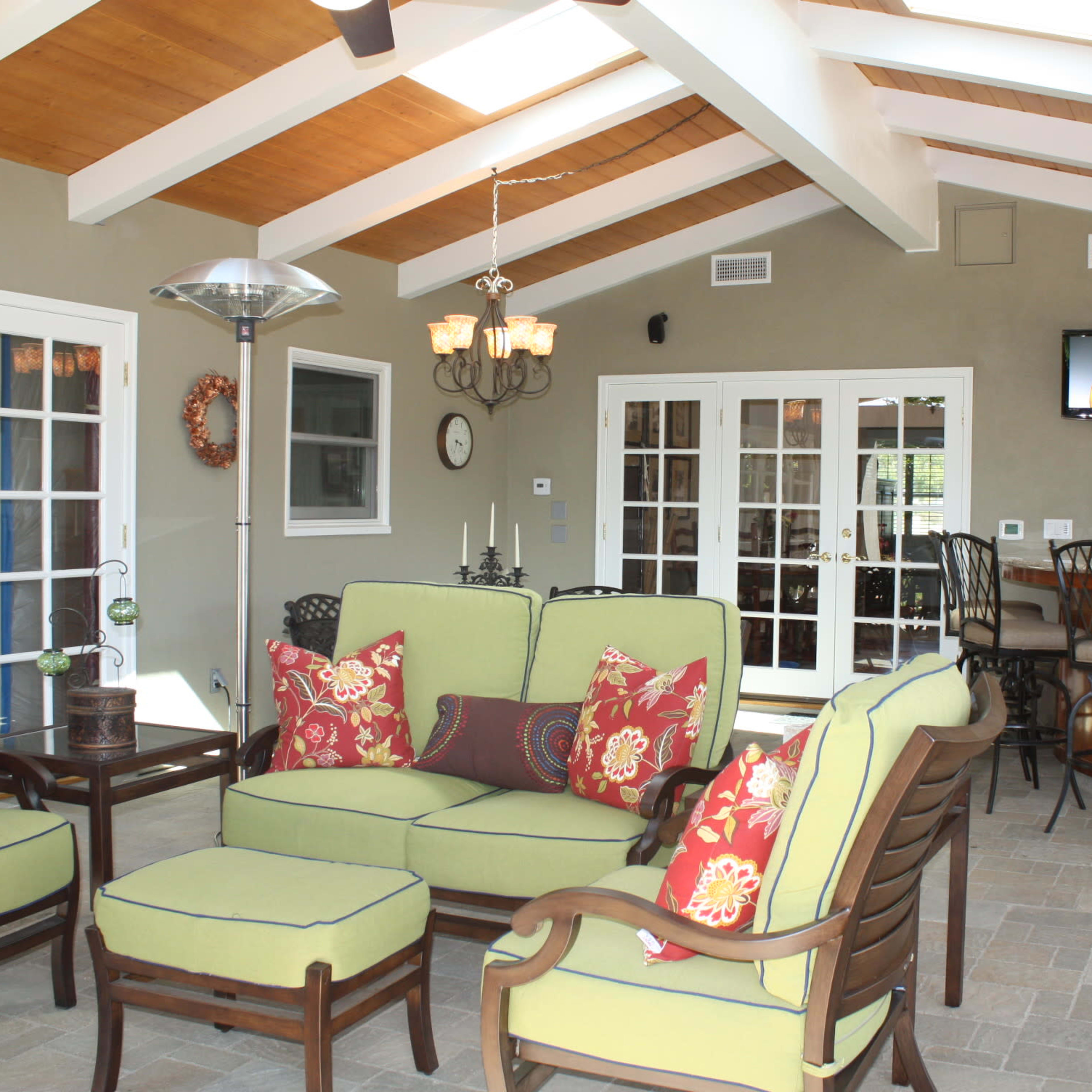 A sunlit indoor seating area with green upholstered furniture and a bar in the background.