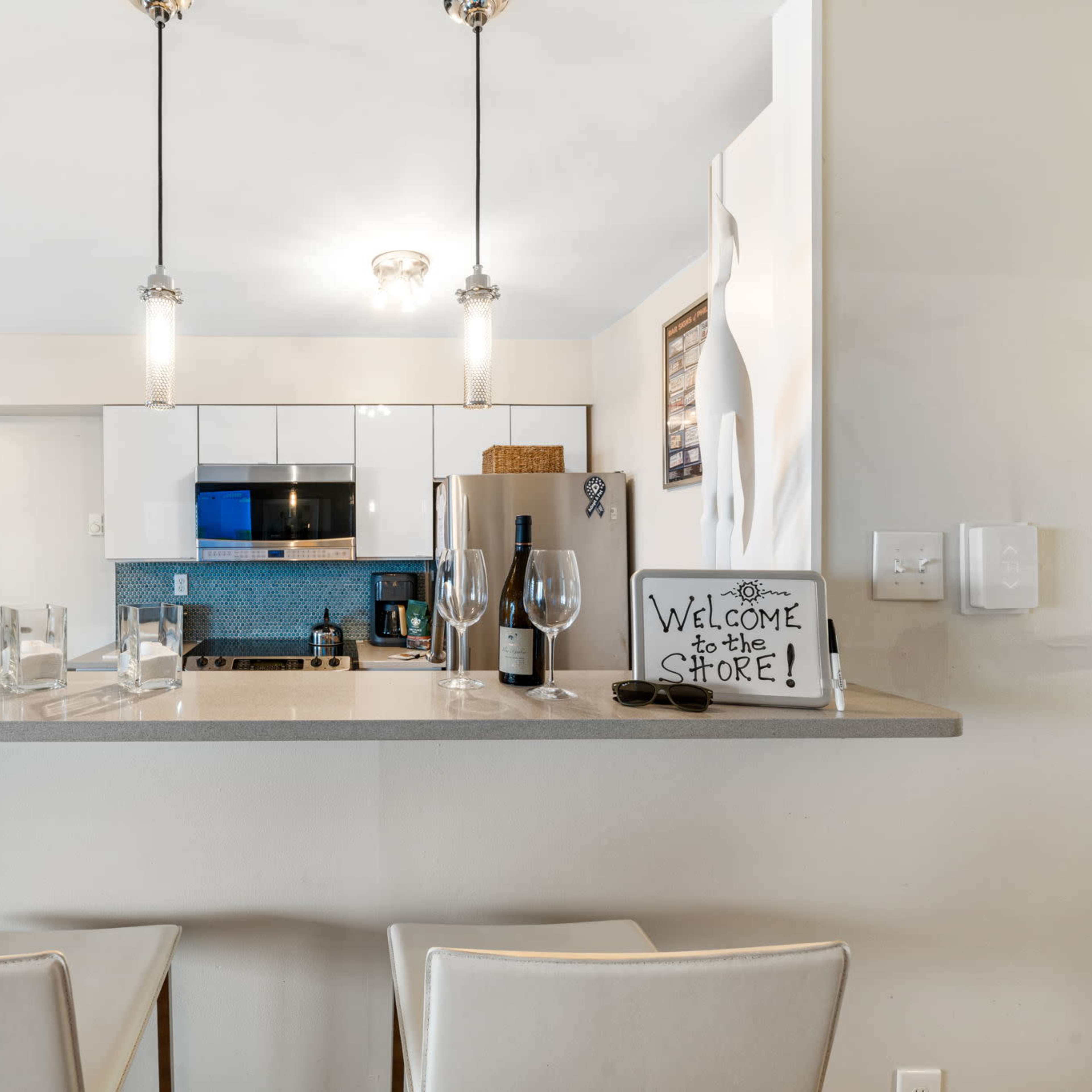 A modern kitchen with a bar countertop, featuring appliances, a small dining area, and decorative elements.