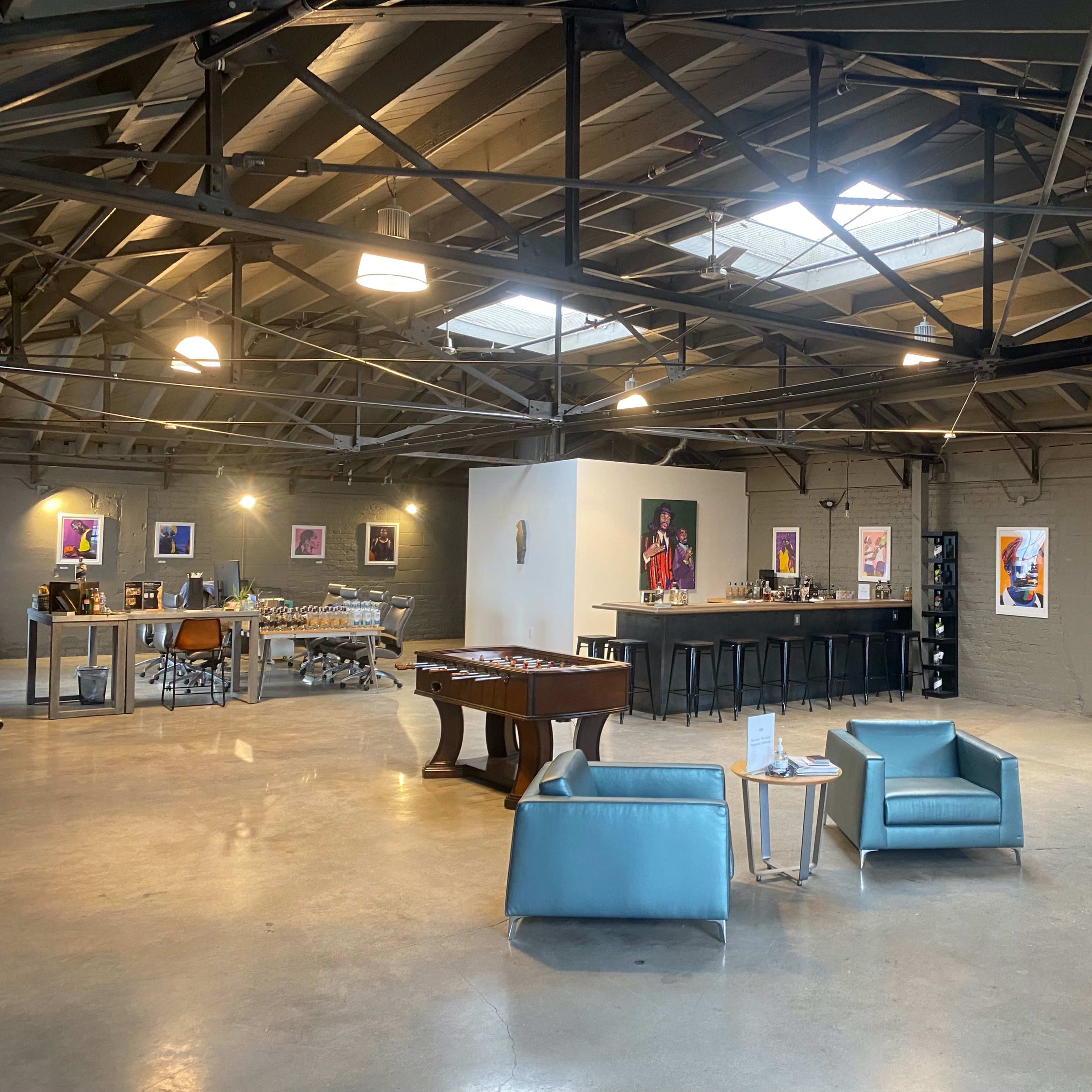 A spacious industrial-style interior with a game table, bar area, and seating arrangements.