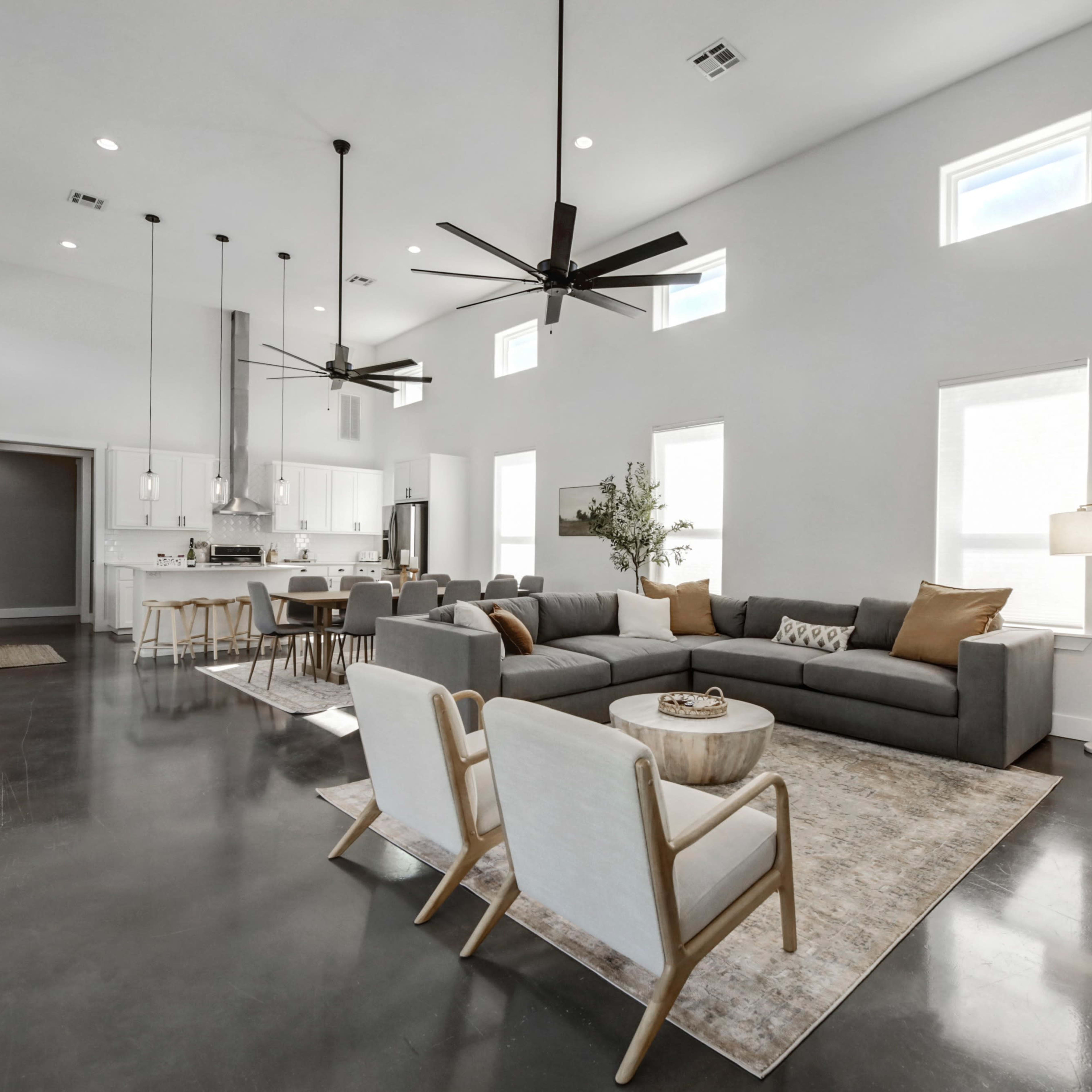 A spacious living area with modern furniture, a large sectional sofa, and a dining space featuring a kitchen in the background.