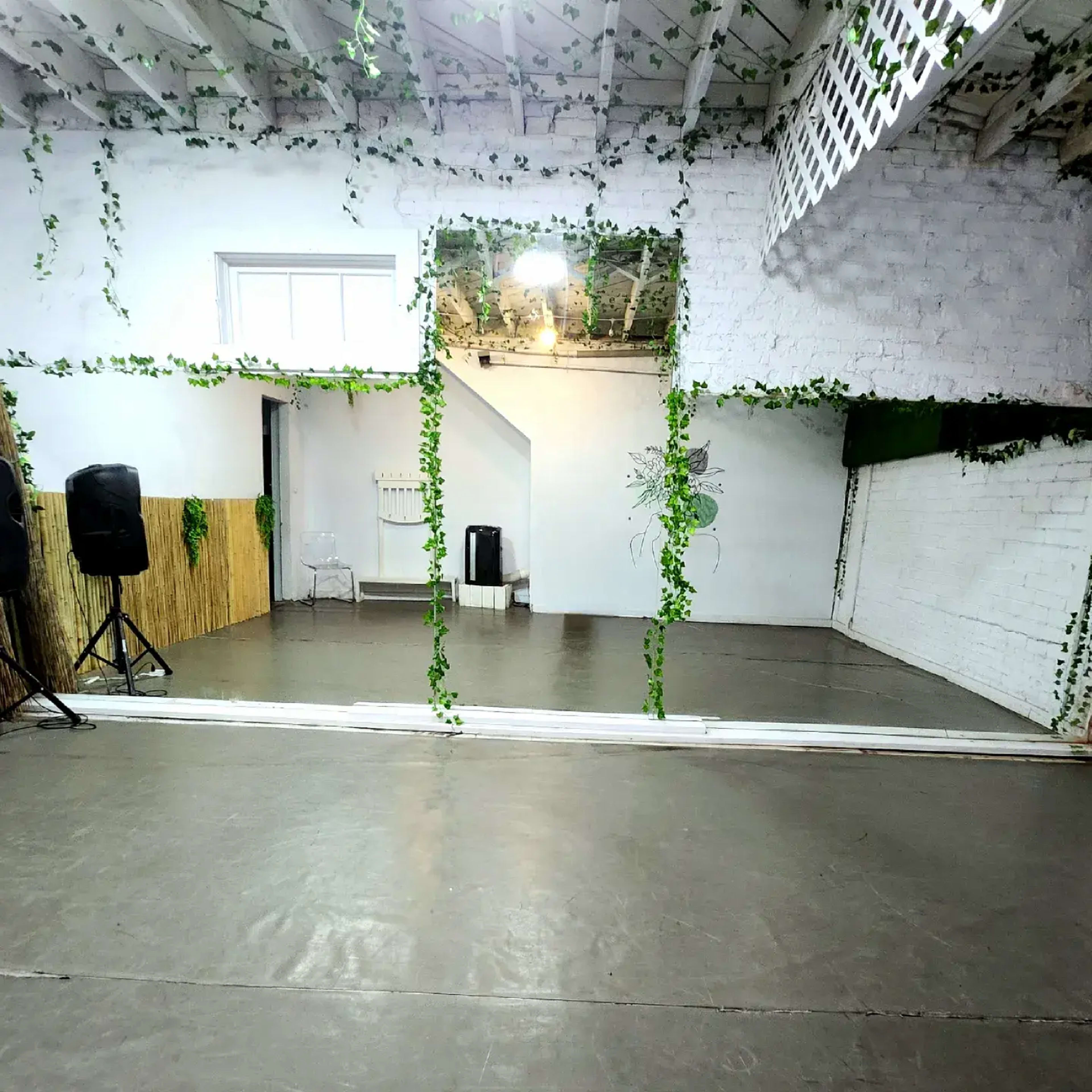 A spacious room with a polished floor, large mirrors, and walls adorned with greenery.