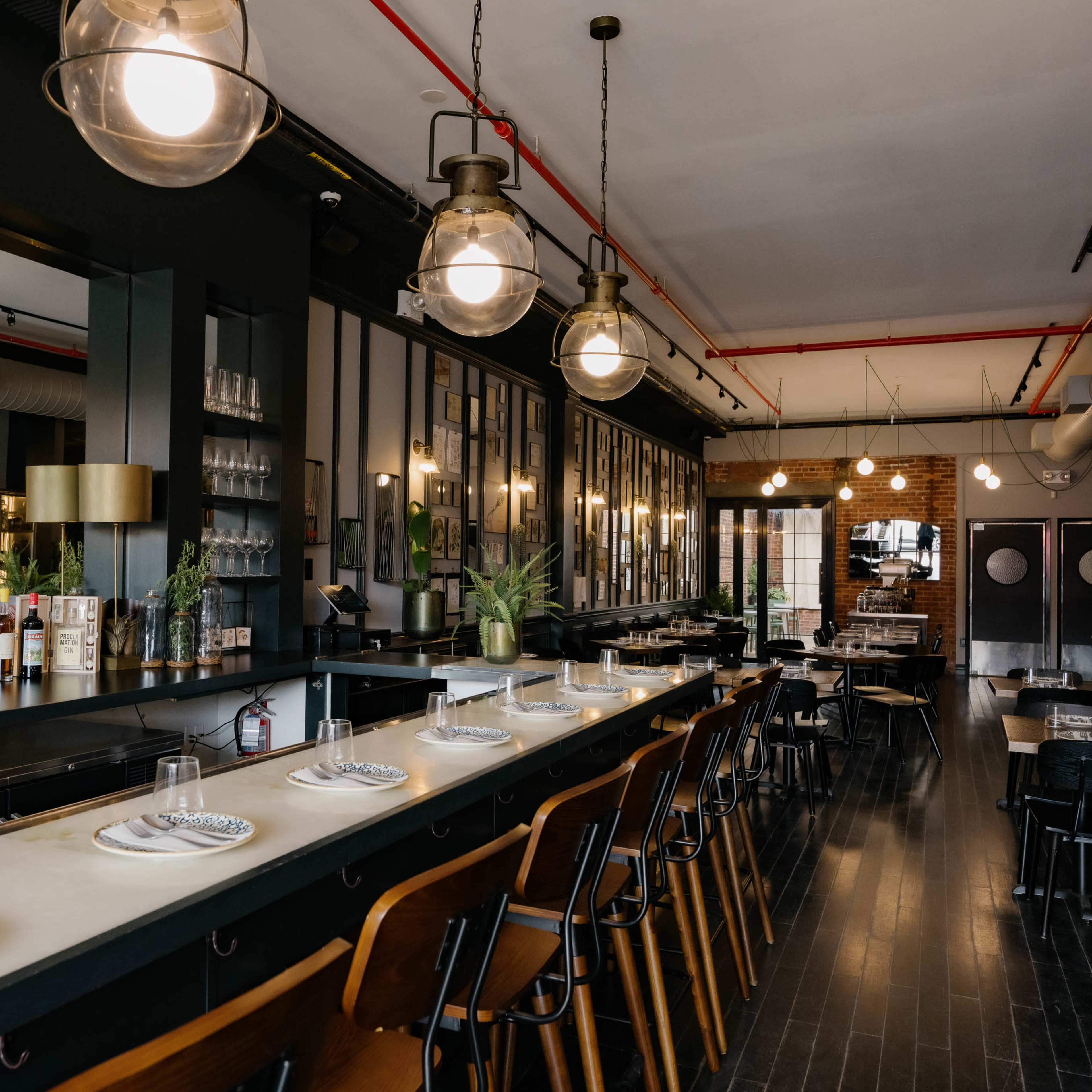 A stylish restaurant interior with a long bar, high-backed chairs, and a well-organized display of liquor and glassware.