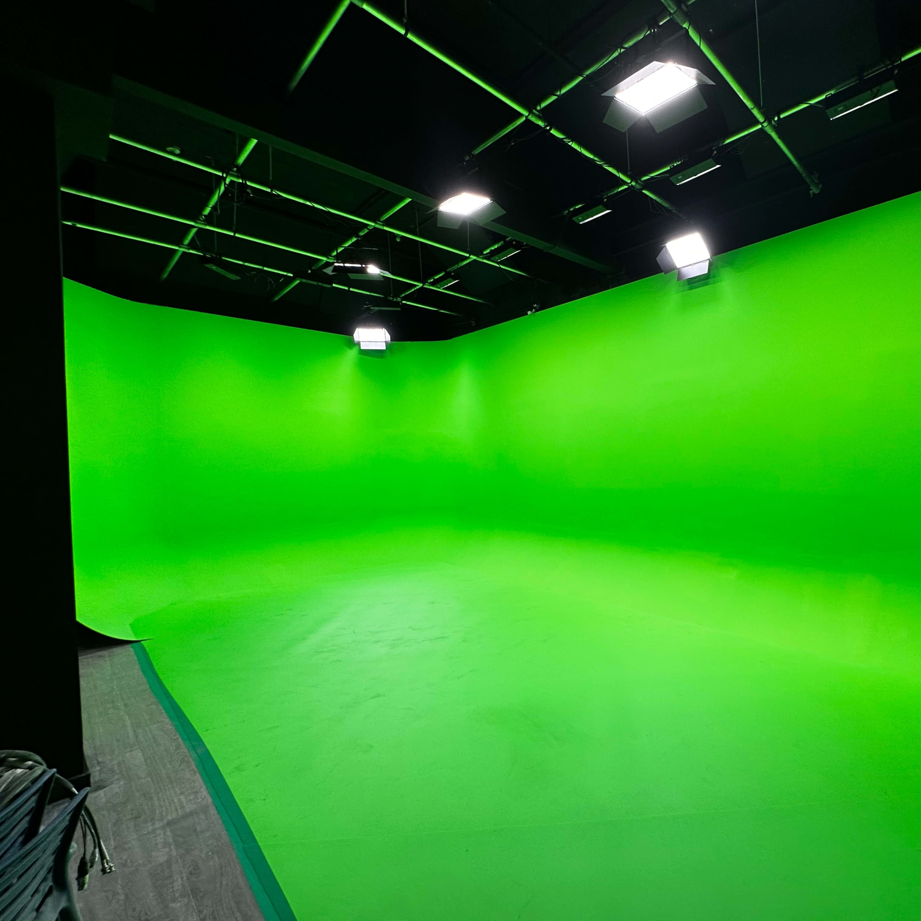 A green screen studio with a smooth green backdrop and bright overhead lights.