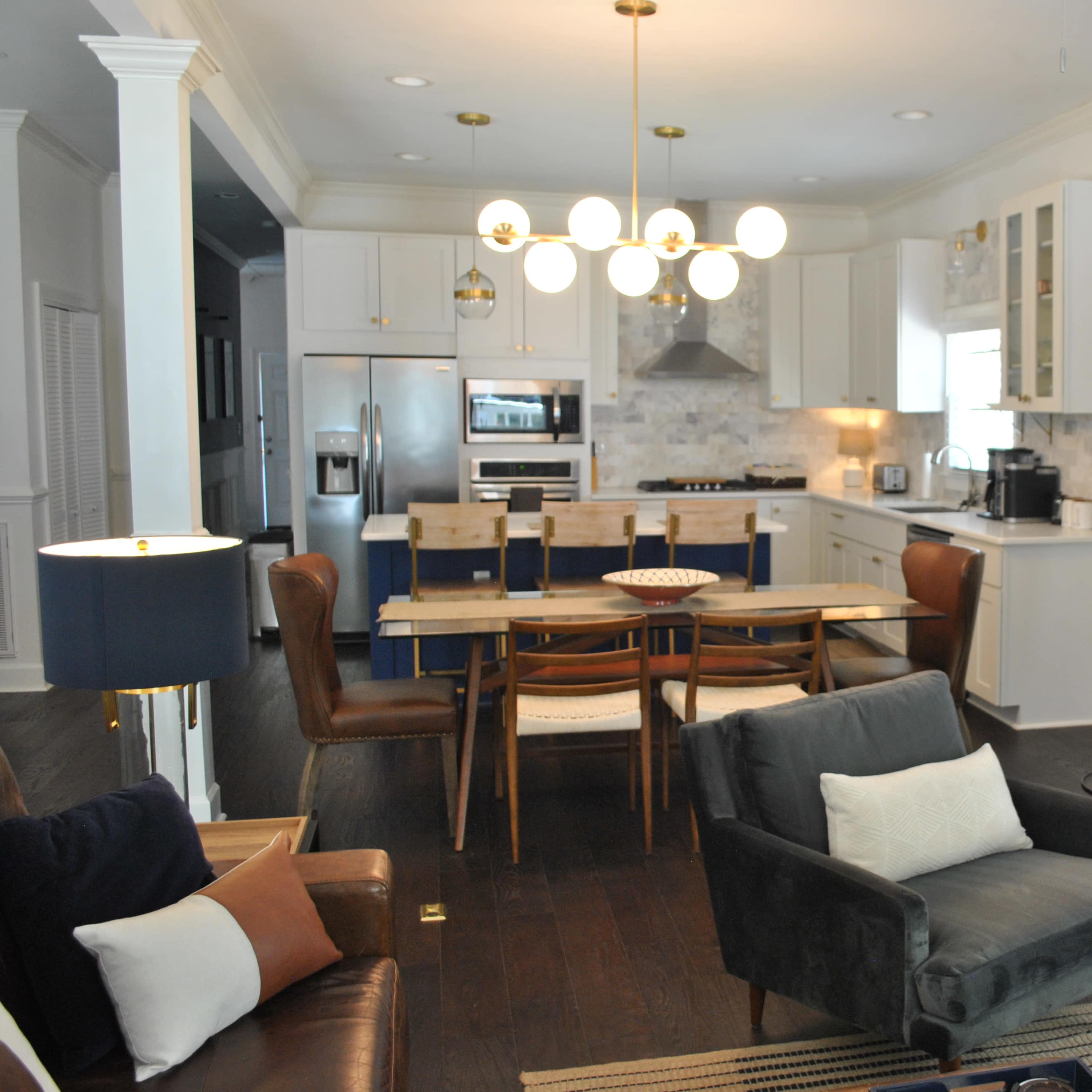 A modern open-concept living area features a dining table, kitchen with stainless steel appliances, and a cozy seating arrangement.