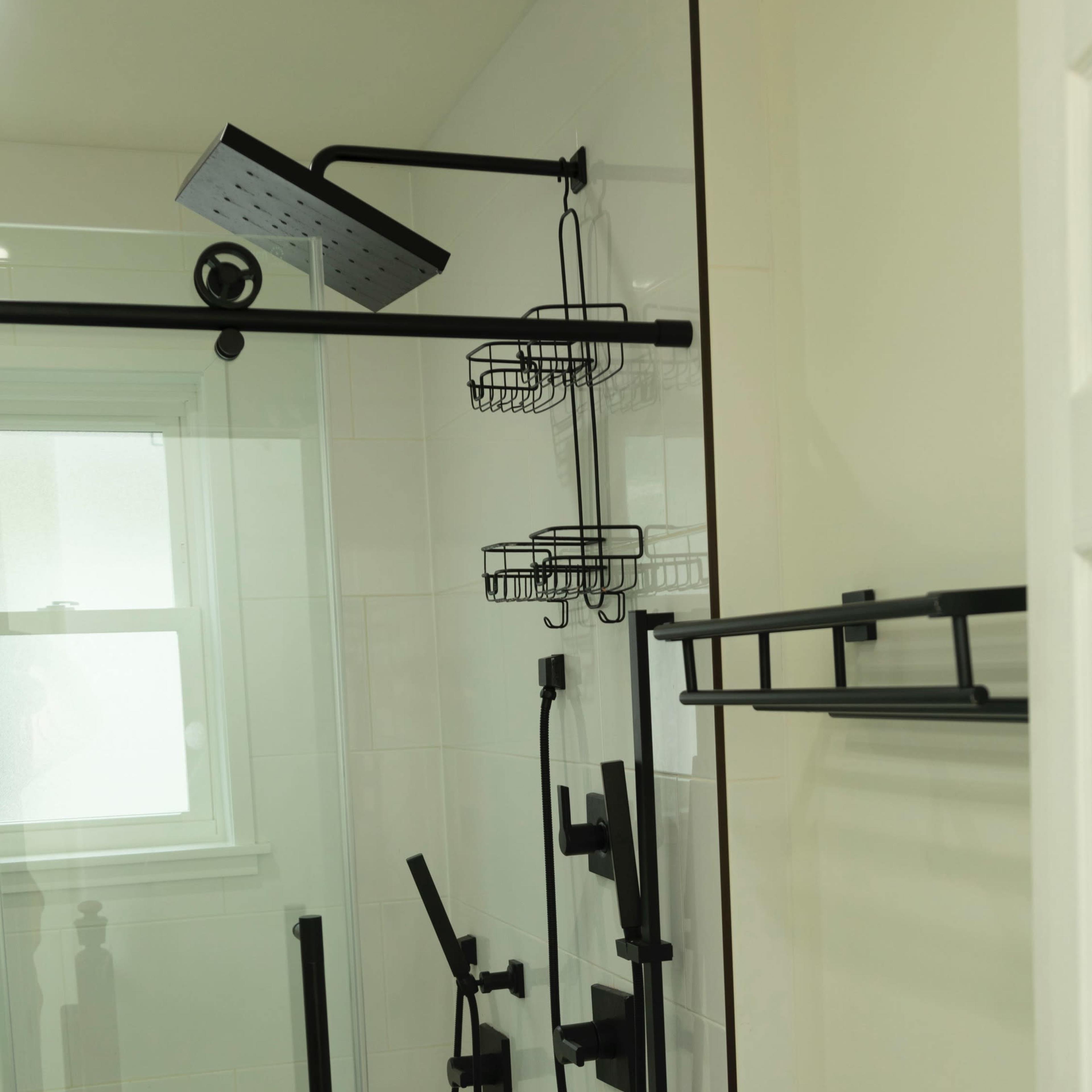A modern shower design featuring a glass enclosure, black fixtures, and a showerhead with an overhead shower arm.