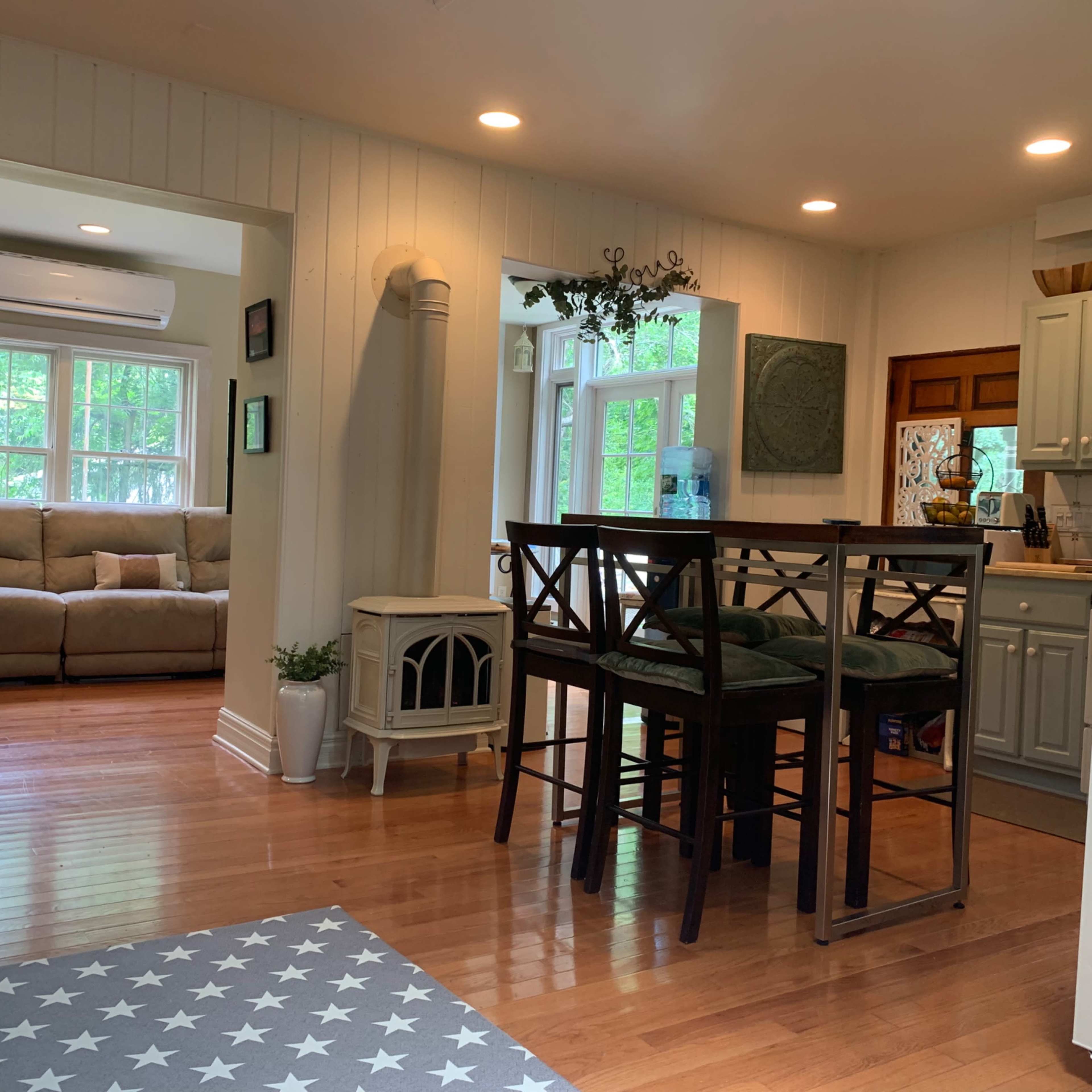 A cozy living space that includes a kitchen with bar stools, a dining area, and a comfortable seating area with a couch.