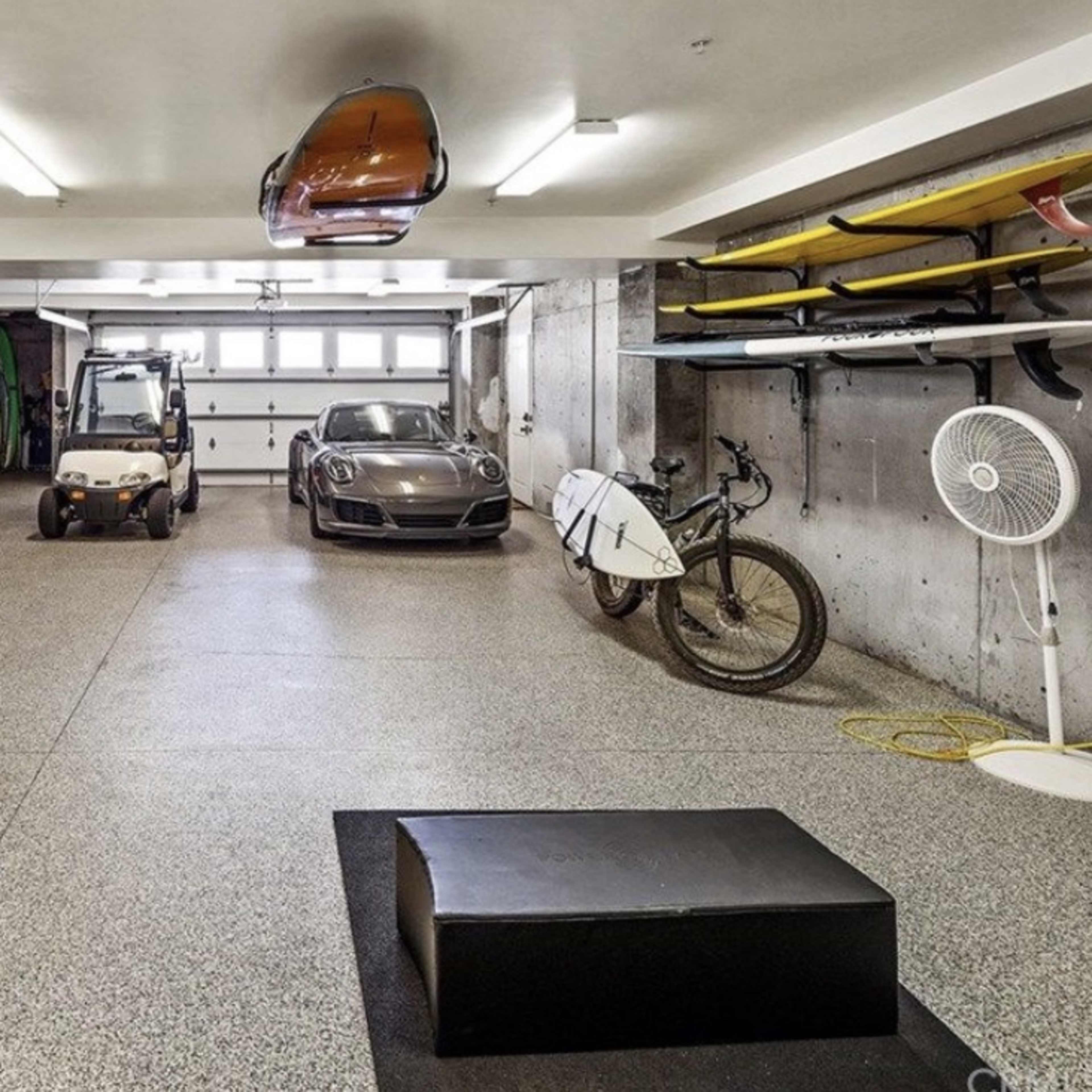 The garage features a car, a golf cart, bicycles, a kayak mounted on the wall, and various storage units.