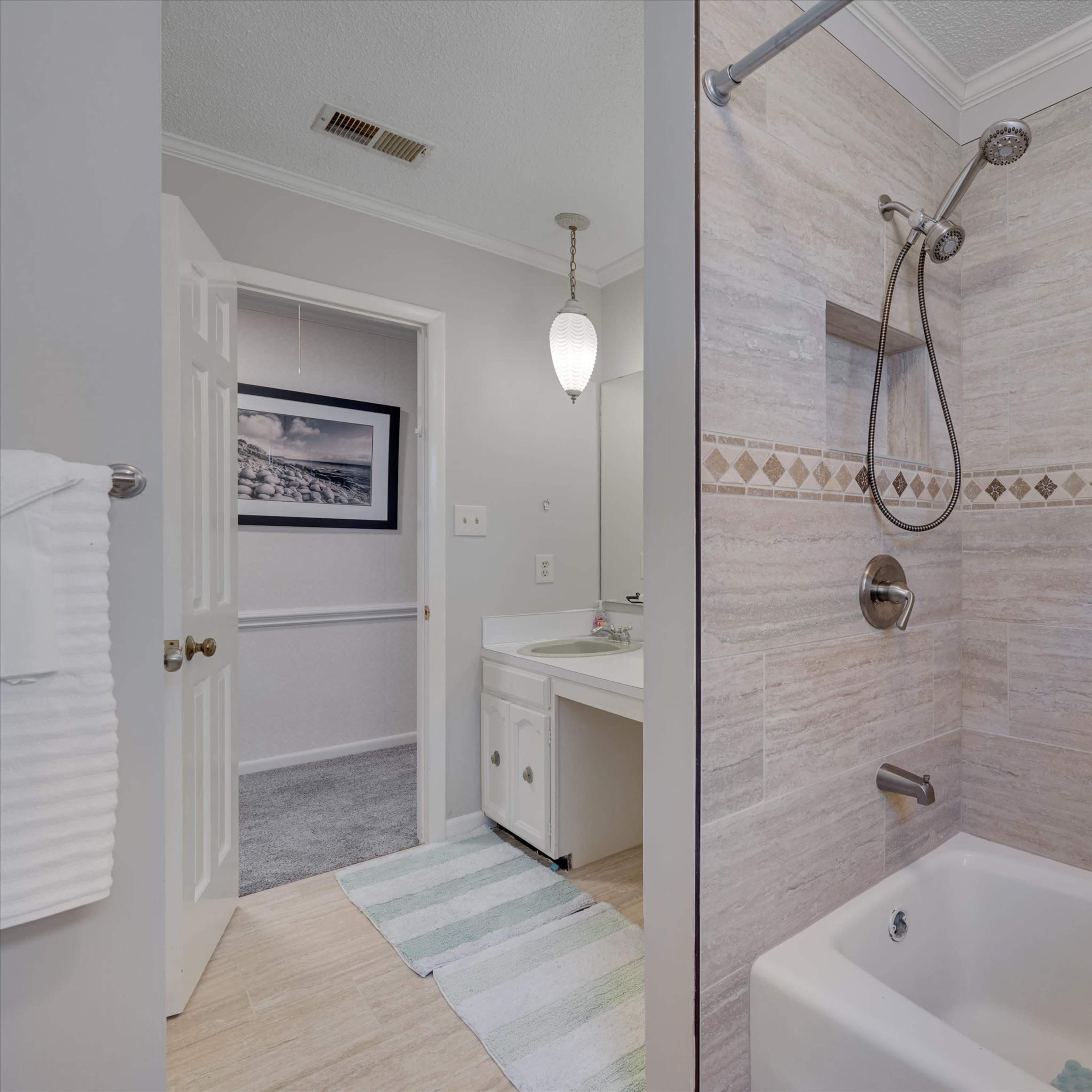 A modern bathroom featuring a shower with a glass partition, a bathtub, and a sink area with a mirror.