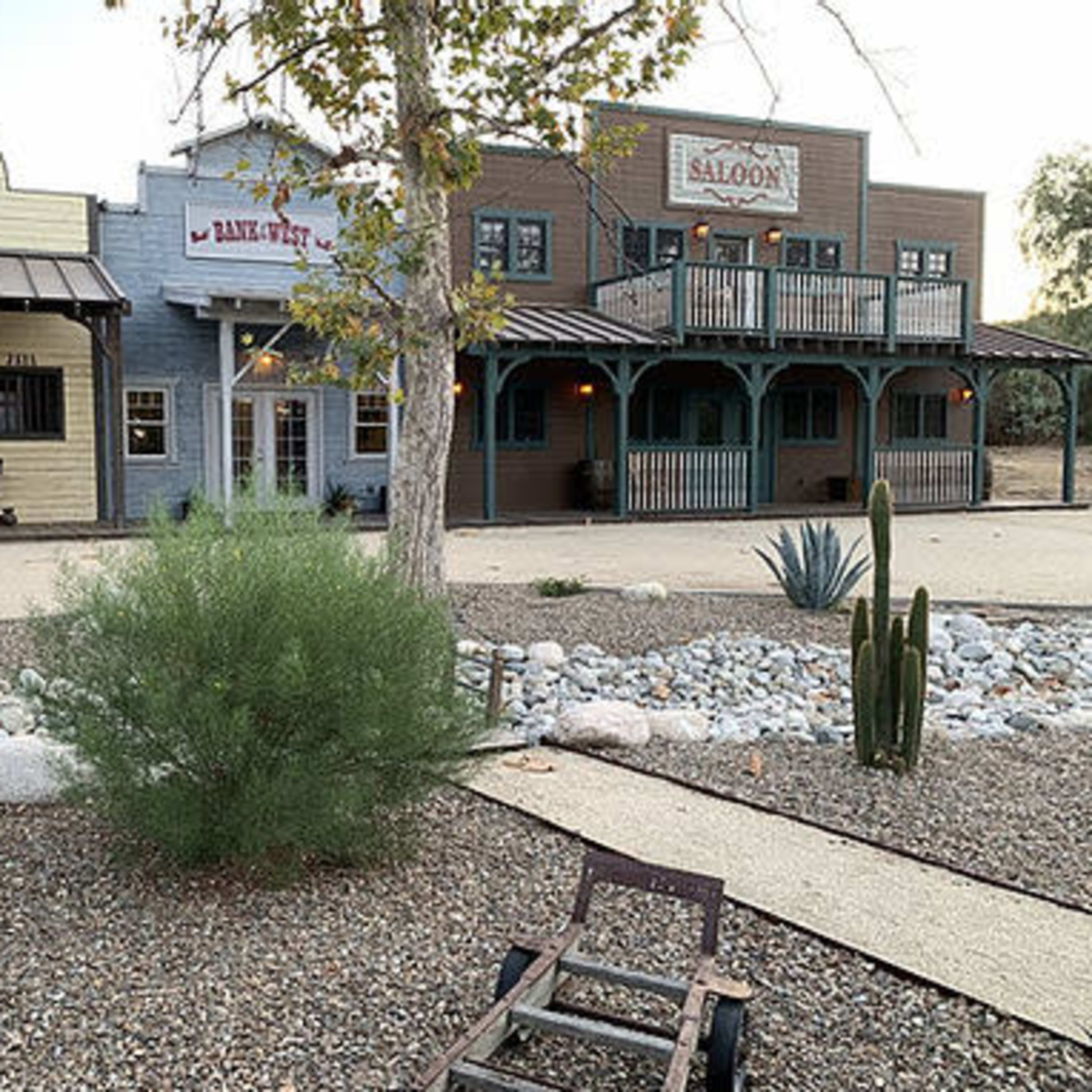 The scene features a western-style town with a sheriff's office, bank, and saloon, surrounded by desert landscaping and gravel pathways.