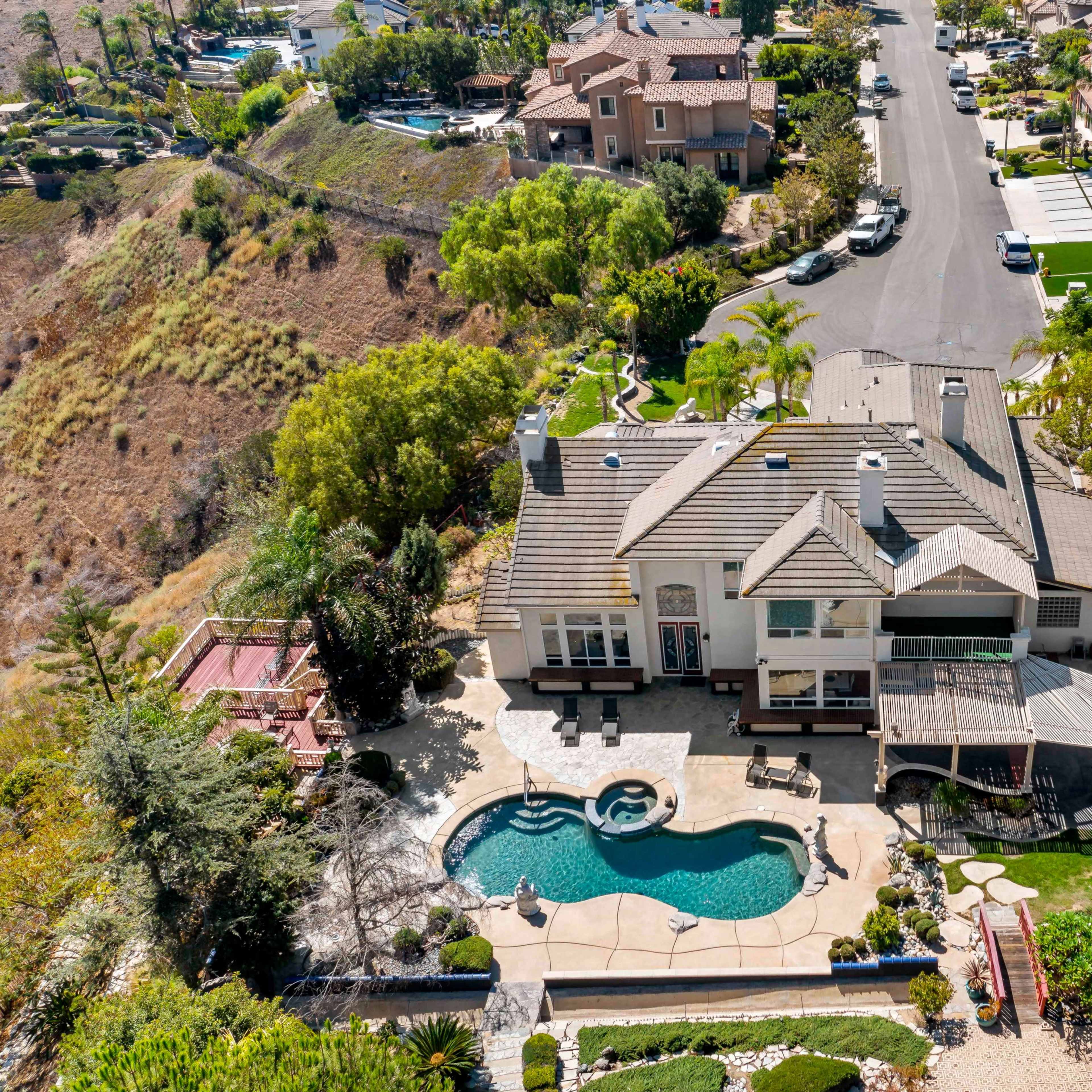 A large residential property with a swimming pool in the backyard, surrounded by other houses on a suburban street.