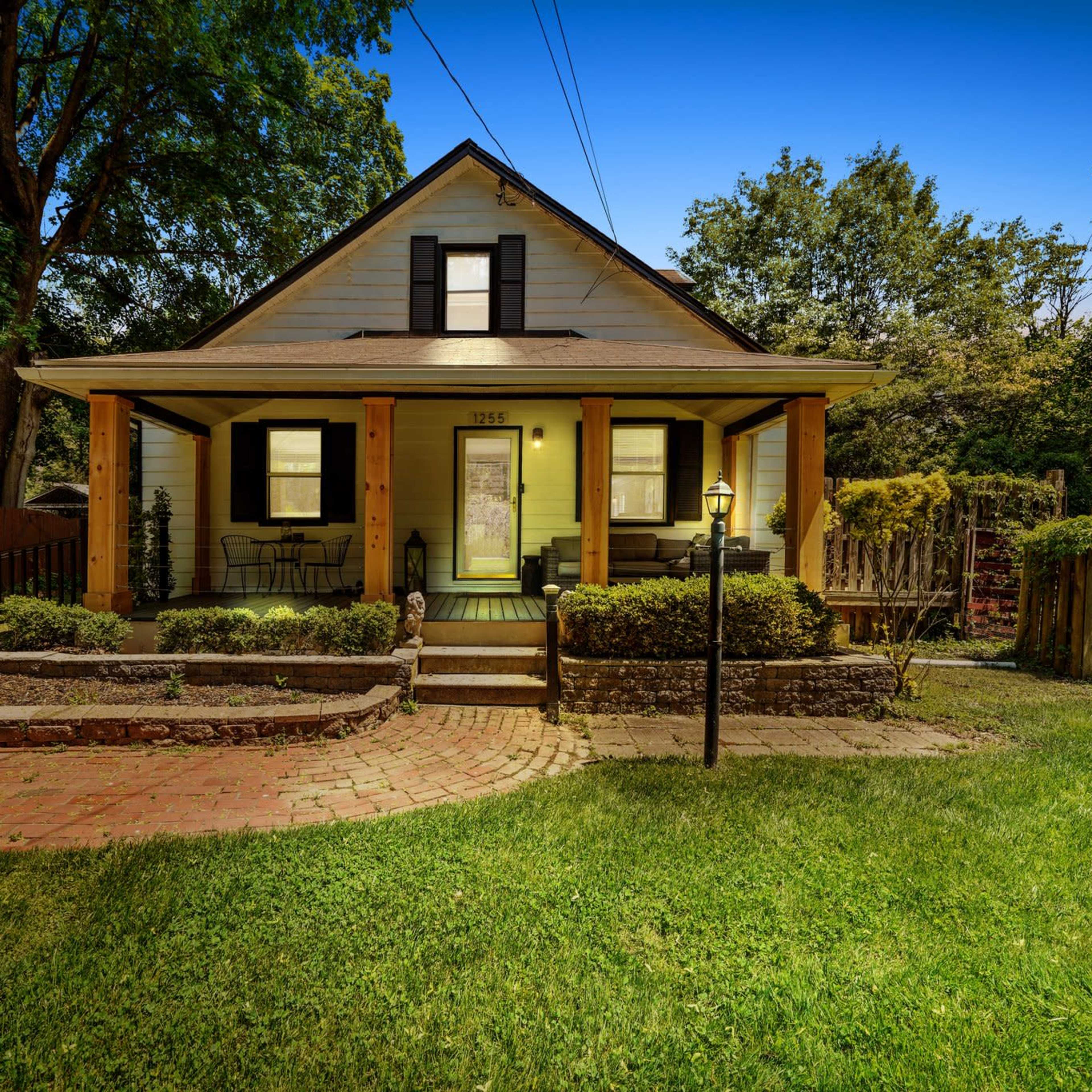 A two-story house with a front porch, surrounded by a well-maintained lawn and garden.
