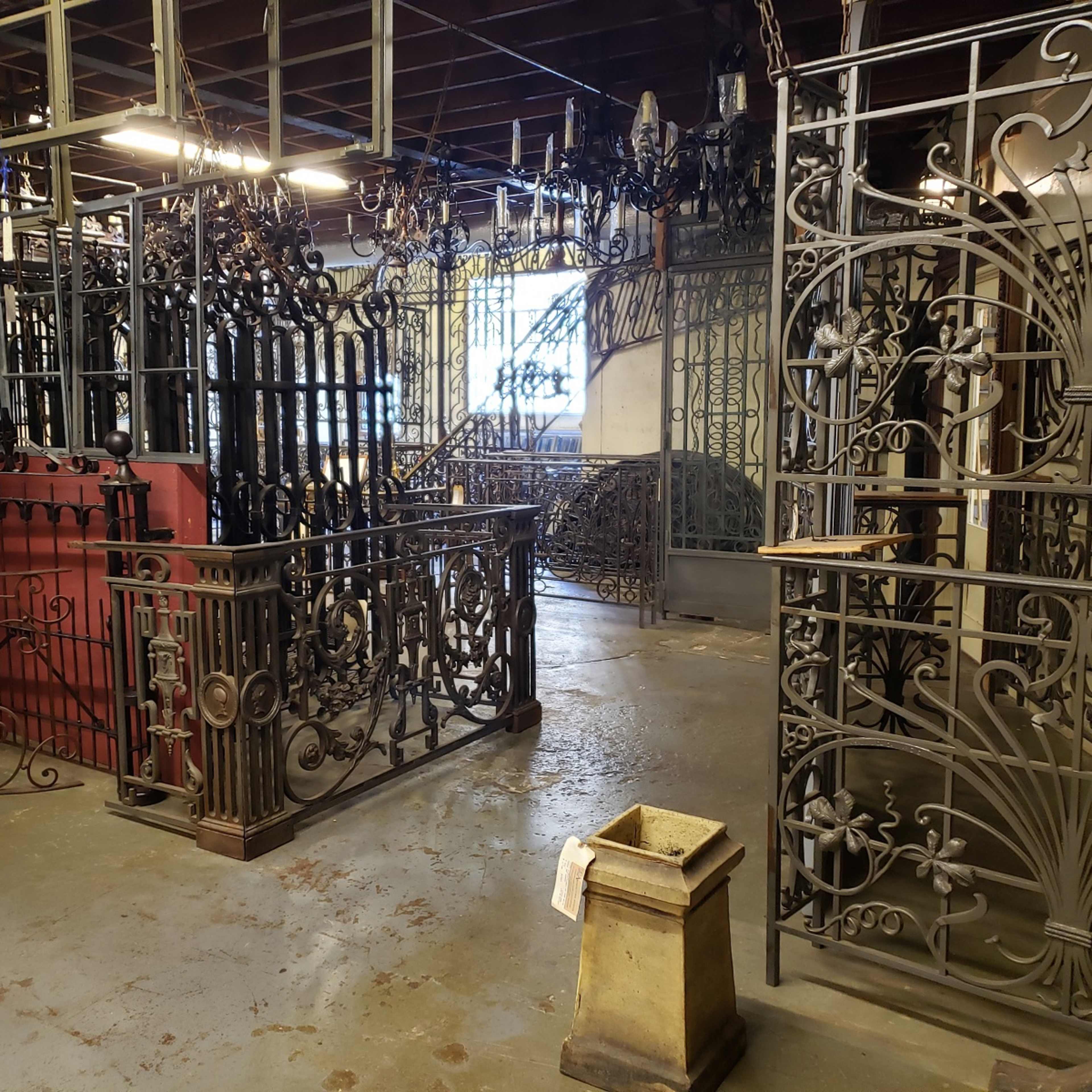 A workshop or storage area filled with various decorative iron gates and fences arranged in a large space.