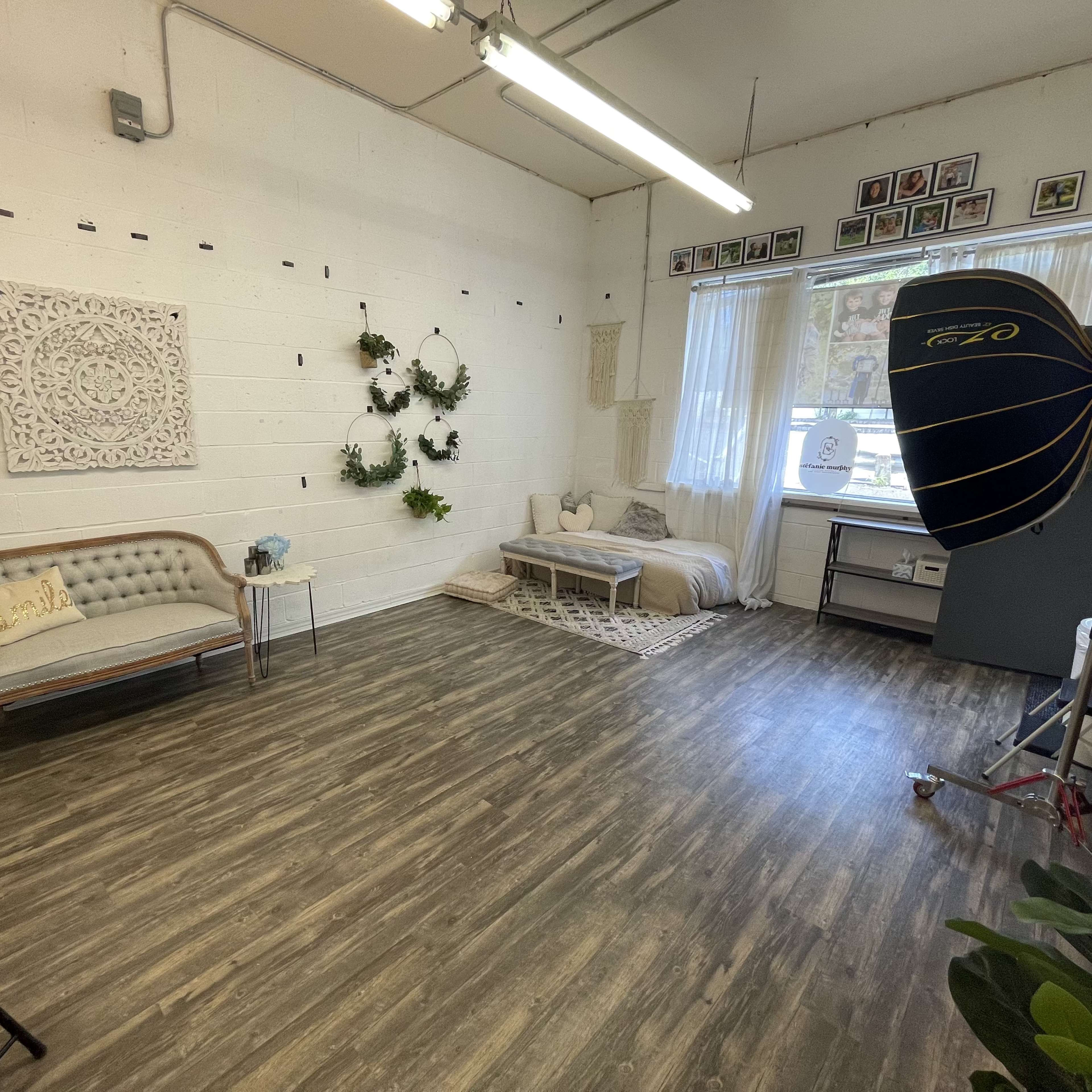 A spacious, well-lit room with a seating area, decorative wall elements, and a photography setup in the corner.