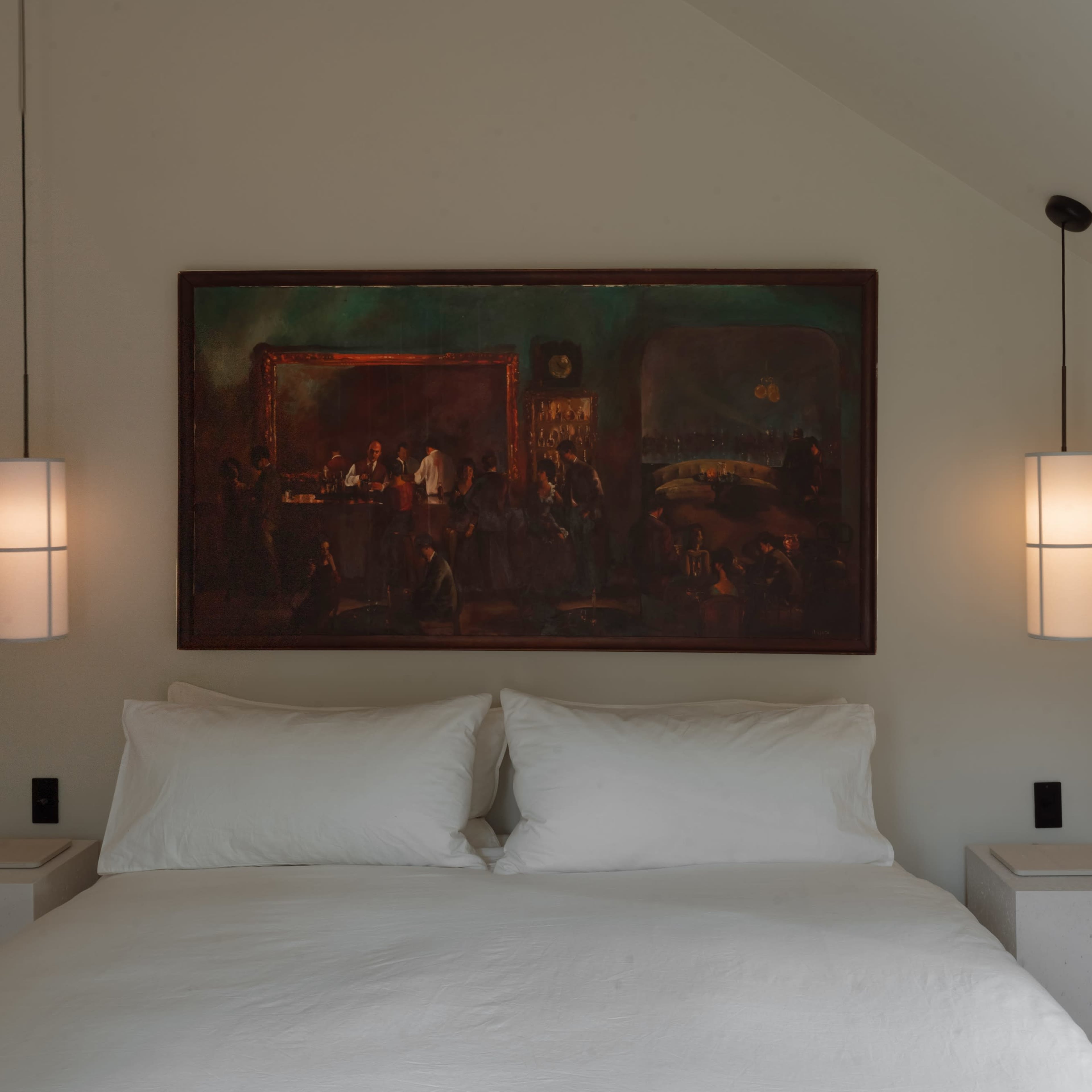 A bedroom with a large painting above a white bed, complemented by two pendant lights on either side of the bed.