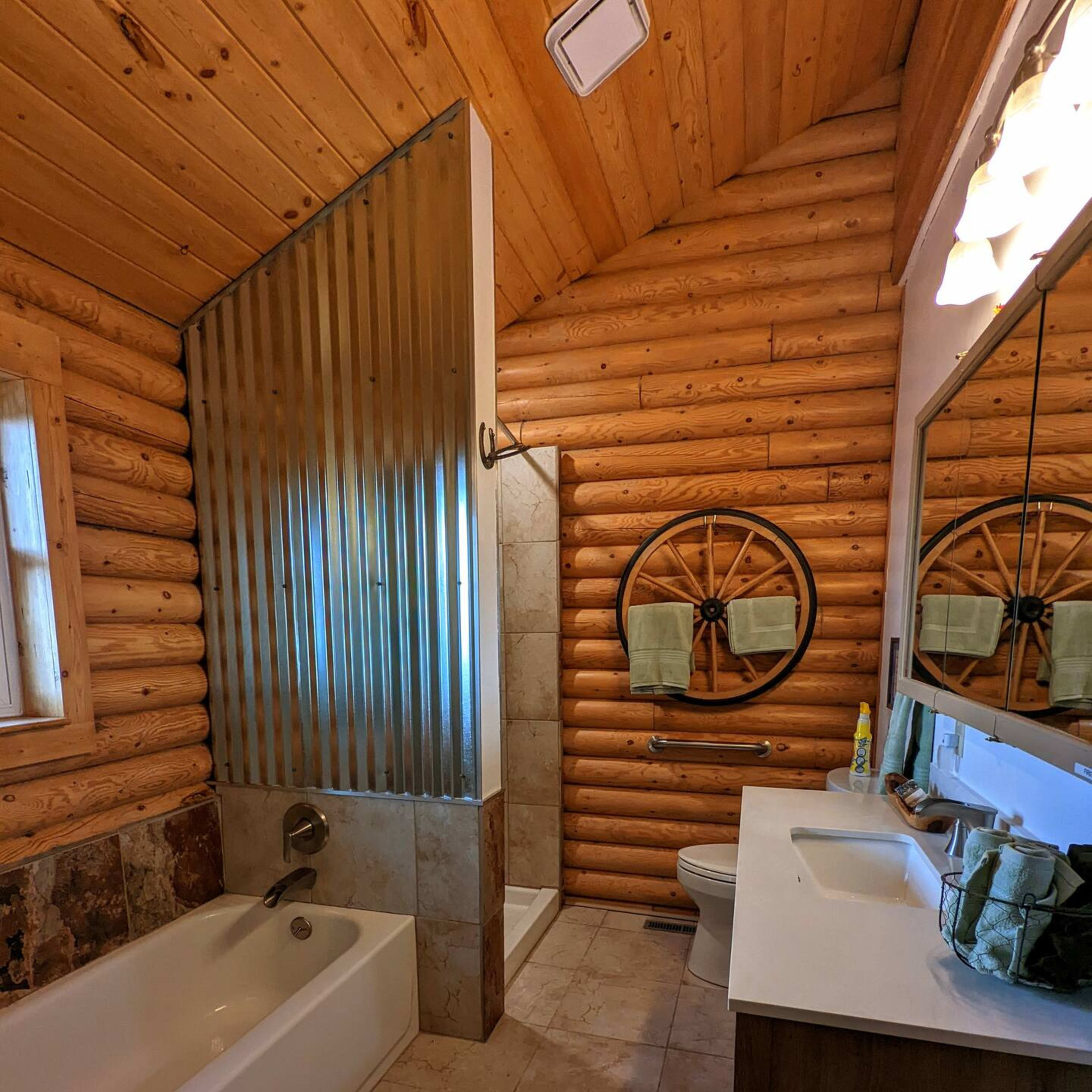 The bathroom features a wooden log cabin design with a freestanding tub, a shower with a metal divider, and a double vanity with mirrors.
