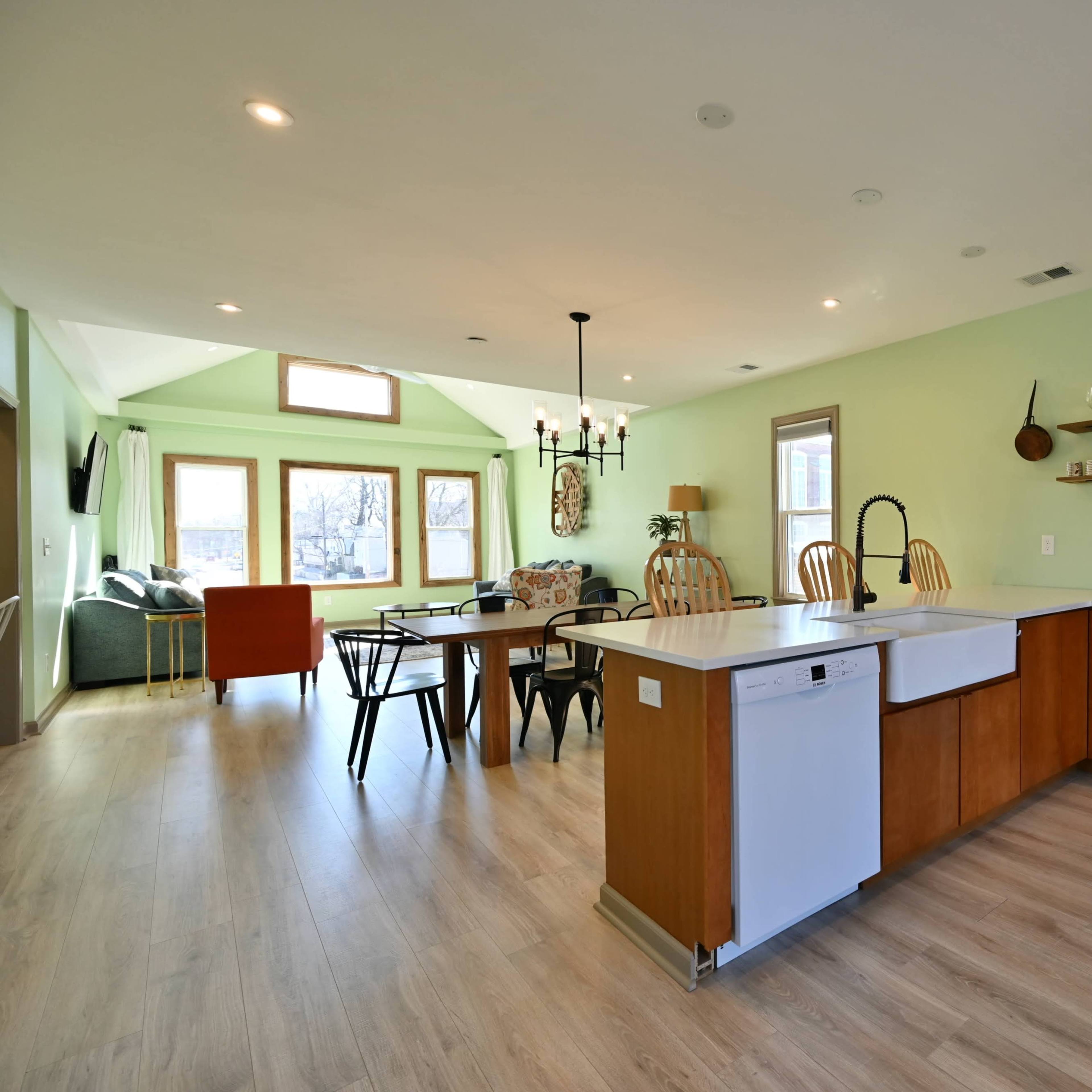 A modern kitchen and dining area with a central island, wooden cabinets, and a dining table surrounded by various chairs.