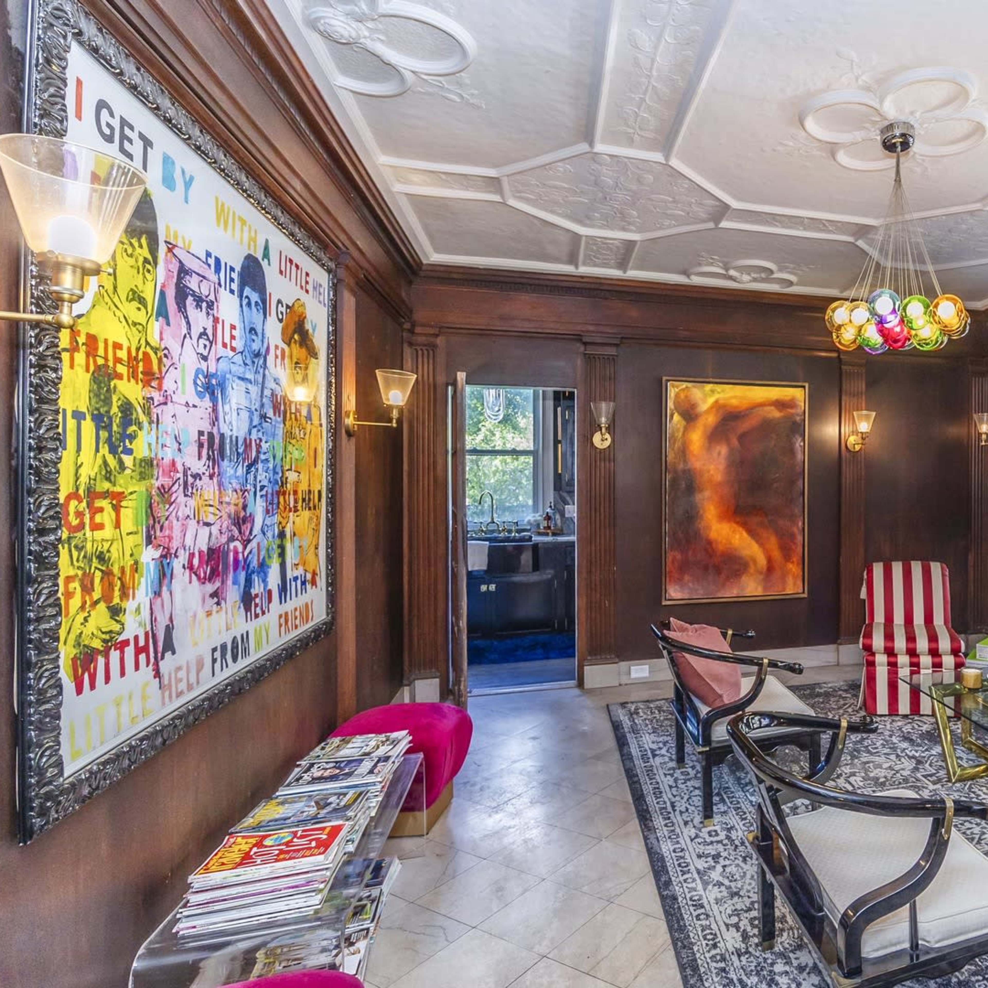 A stylish living room featuring a leather sofa, armchairs, a coffee table, and decorative art on the walls.