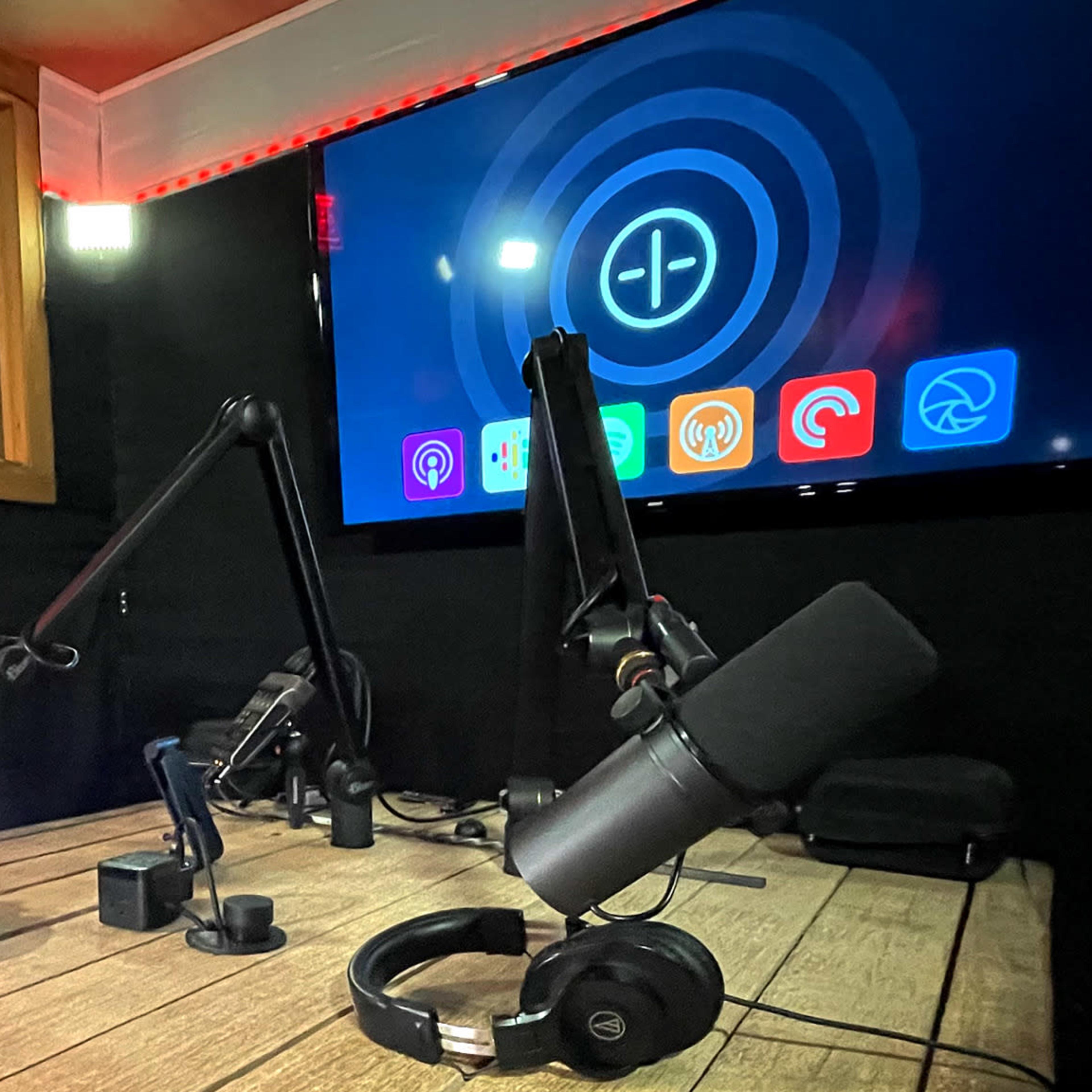 A podcast studio featuring multiple microphones, headphones, and a large screen displaying an app interface.