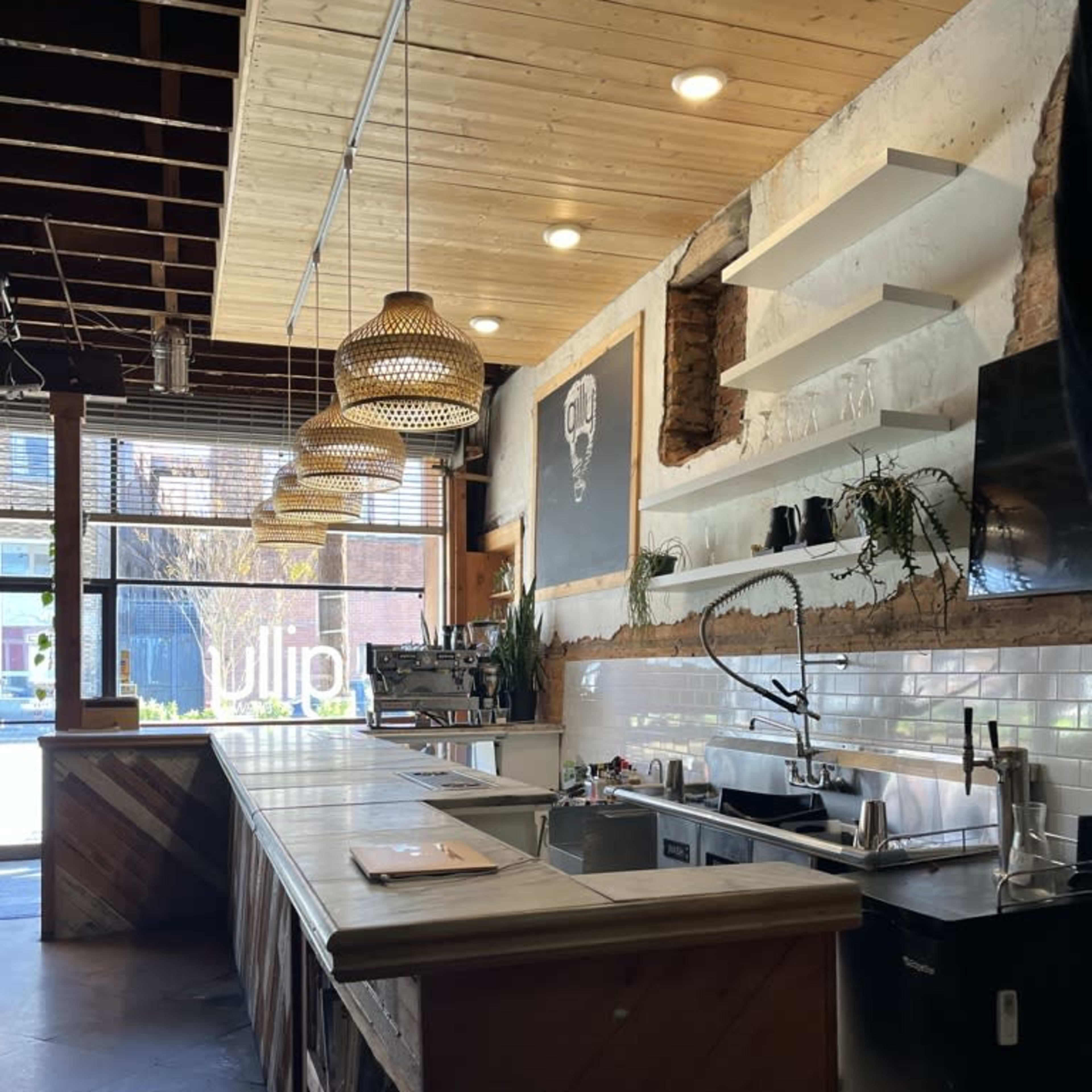 A modern kitchen with a wooden counter, exposed brick wall, and pendant lights hanging from the ceiling.