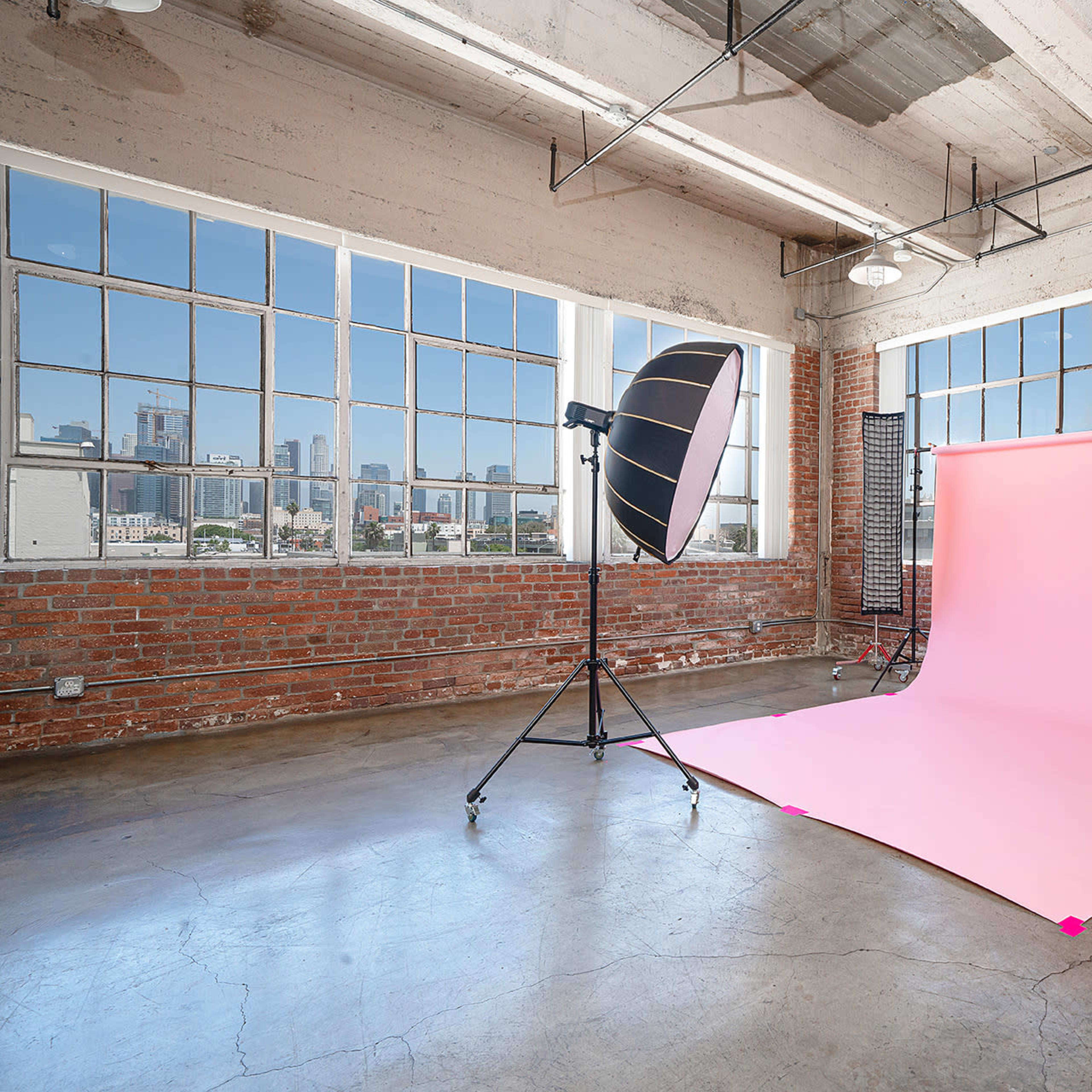 A photography studio with a seamless backdrop, lighting equipment, and exposed brick walls.