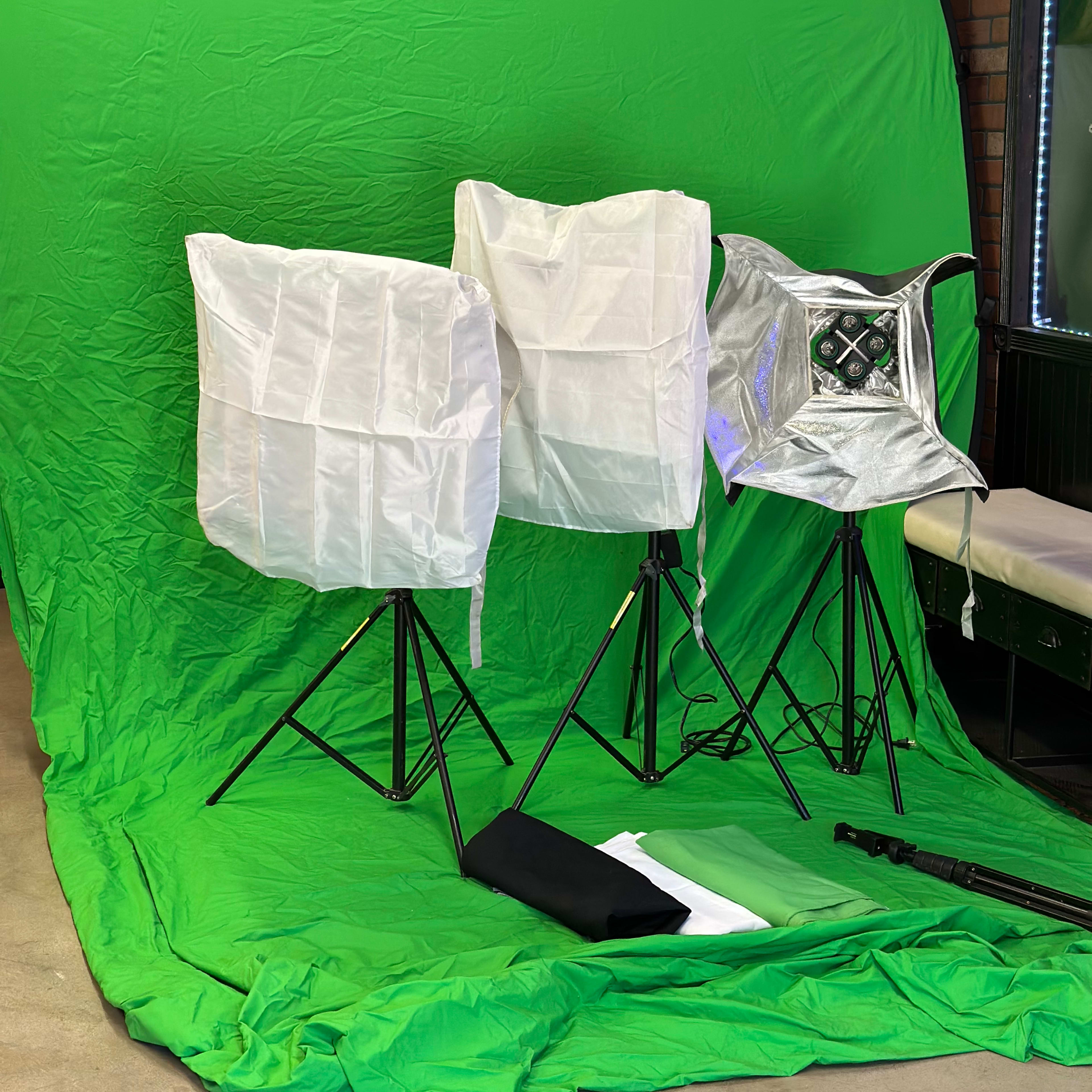 Three lighting softboxes positioned in front of a green backdrop.