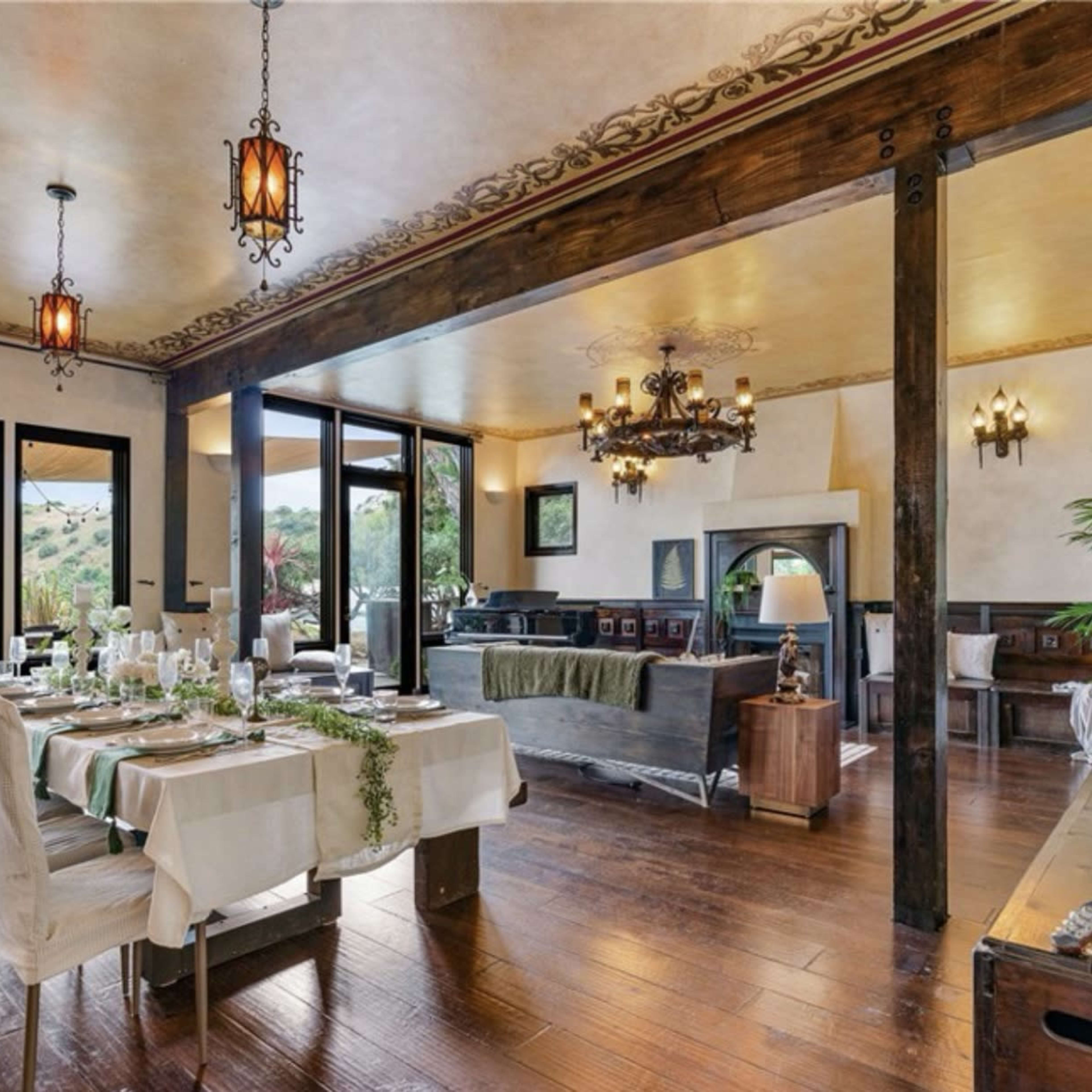 A spacious dining area with a long table set for a meal, surrounded by large windows that overlook a scenic view.