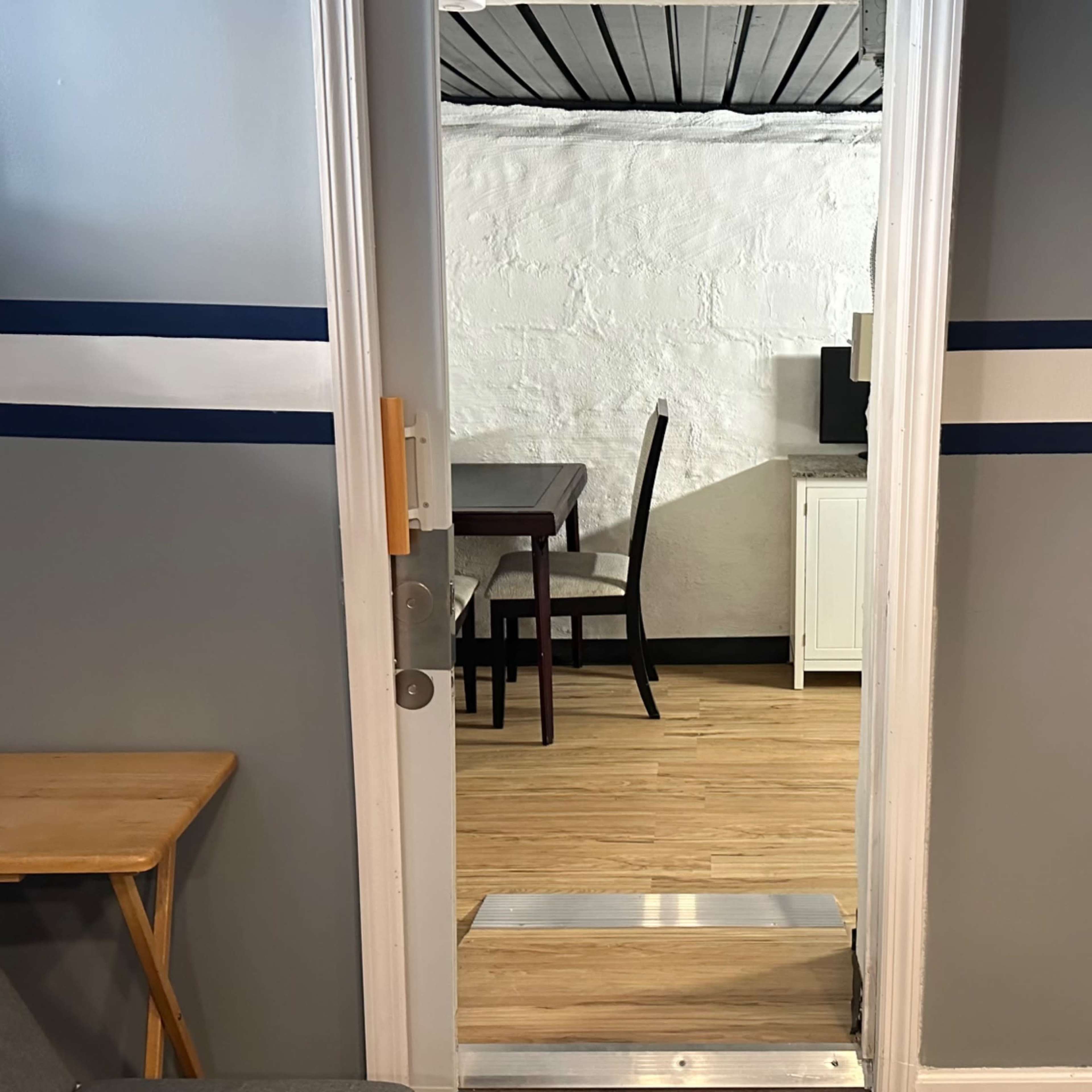 An open doorway leading into a room with a dining table and chairs in a well-lit space.