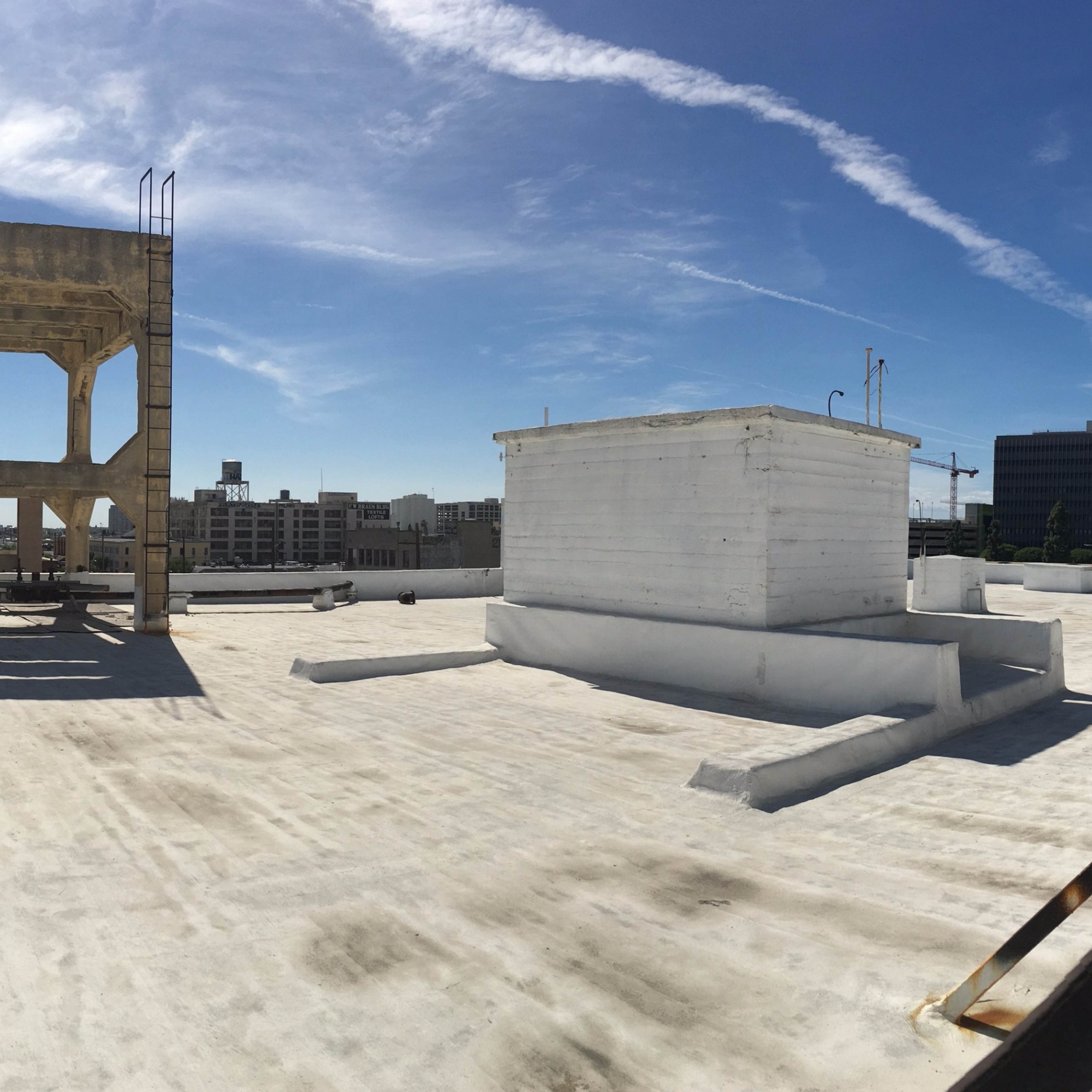 A panoramic view of a flat rooftop with industrial structures and a clear blue sky above.