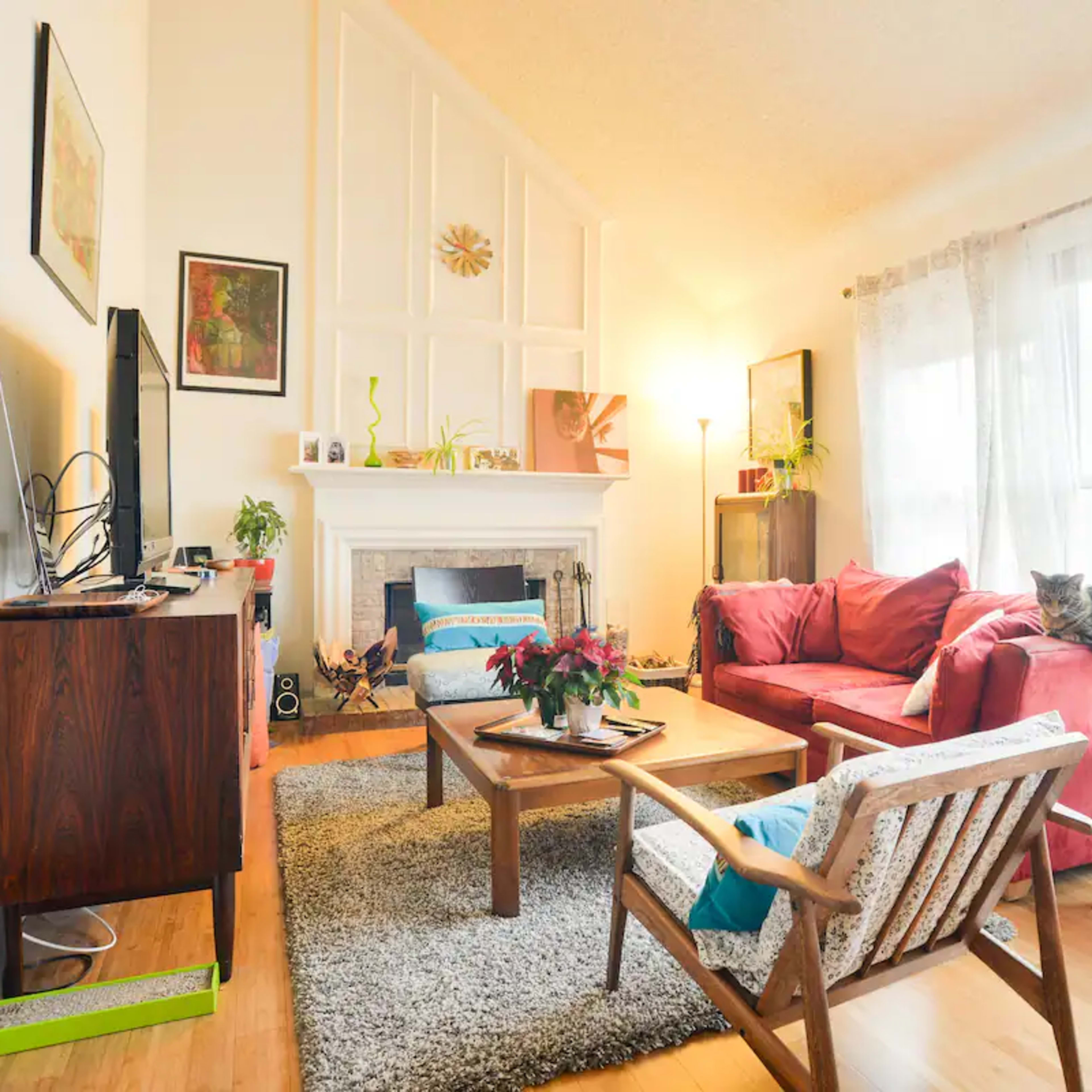 A cozy living room with a red sofa, a coffee table, and large windows that allow natural light to fill the space.