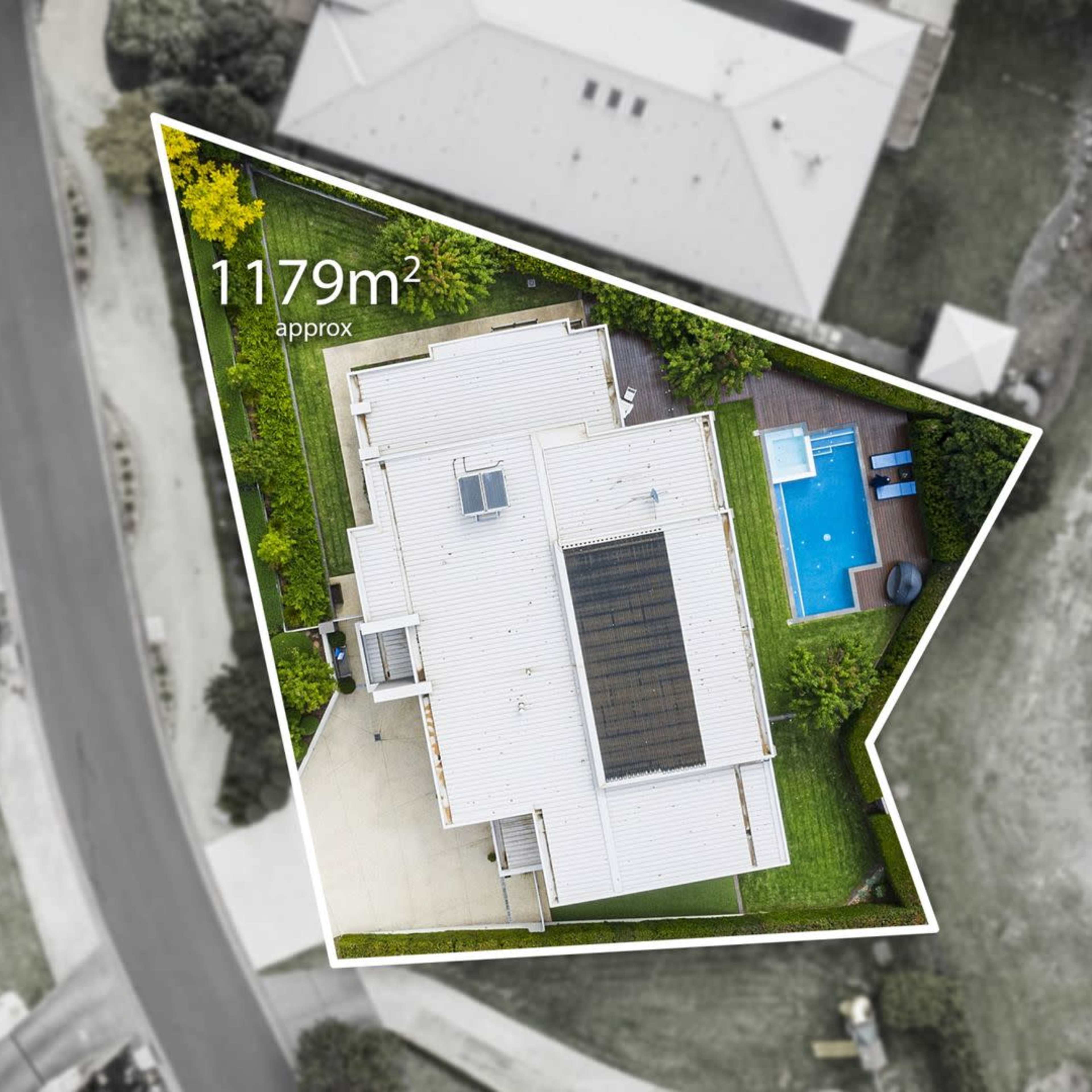 An aerial view of a triangular residential property with a pool in the backyard and surrounding houses.