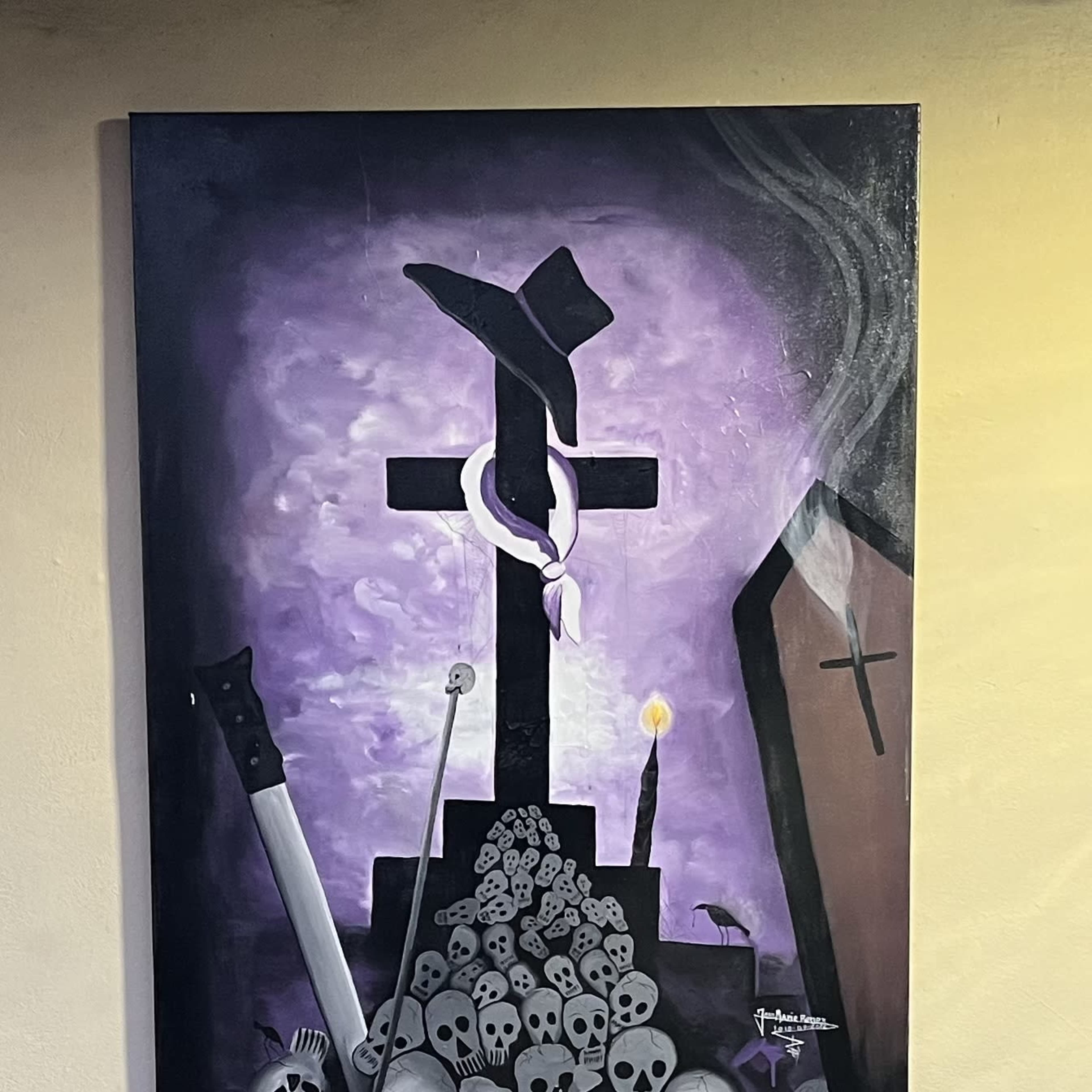 A painting of a graveyard scene, with a cross and tombstones surrounded by skulls, complemented by a purple background and an urn placed below it.