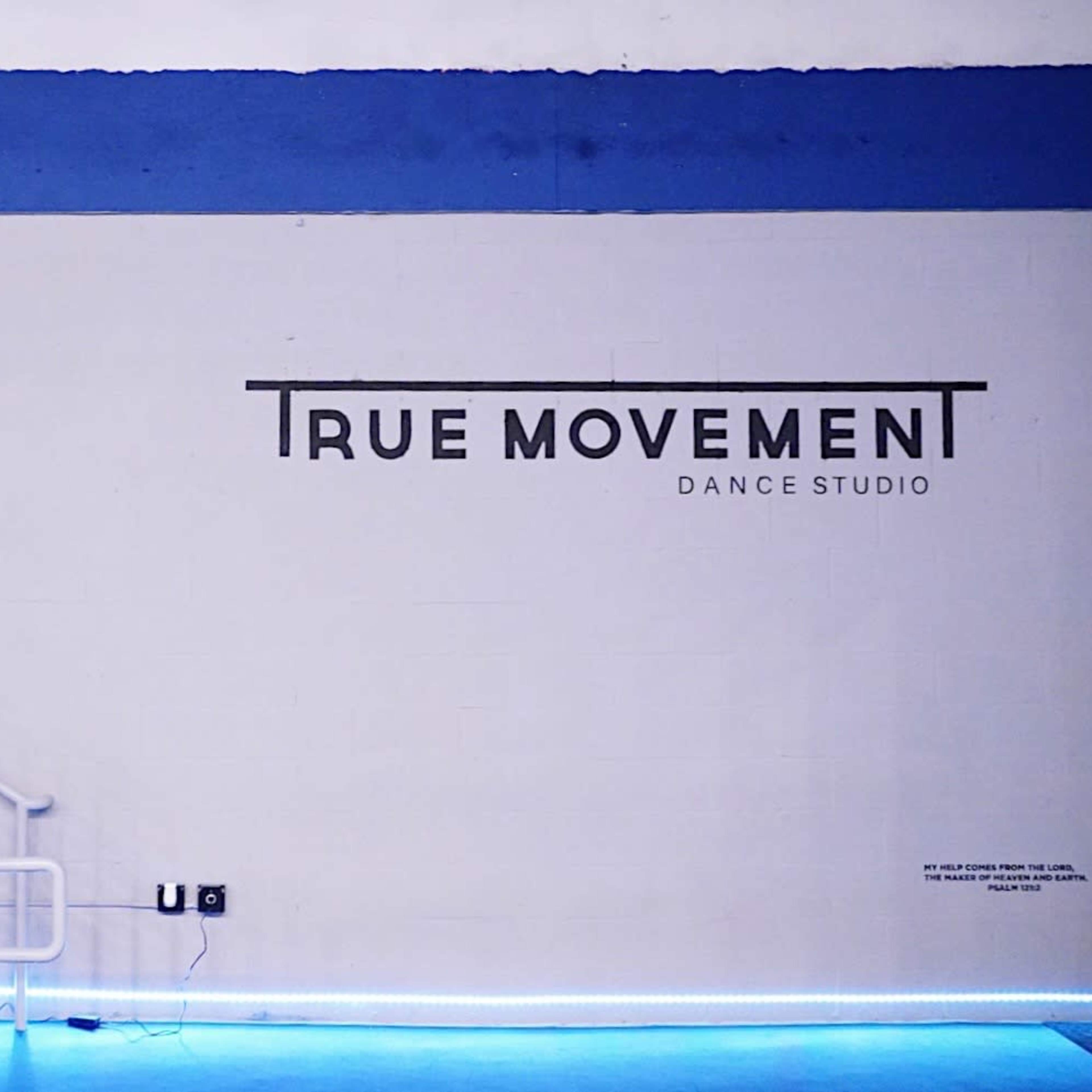 A staircase next to a blue and white wall featuring the text "TRUE MOVEMENT DANCE STUDIO."