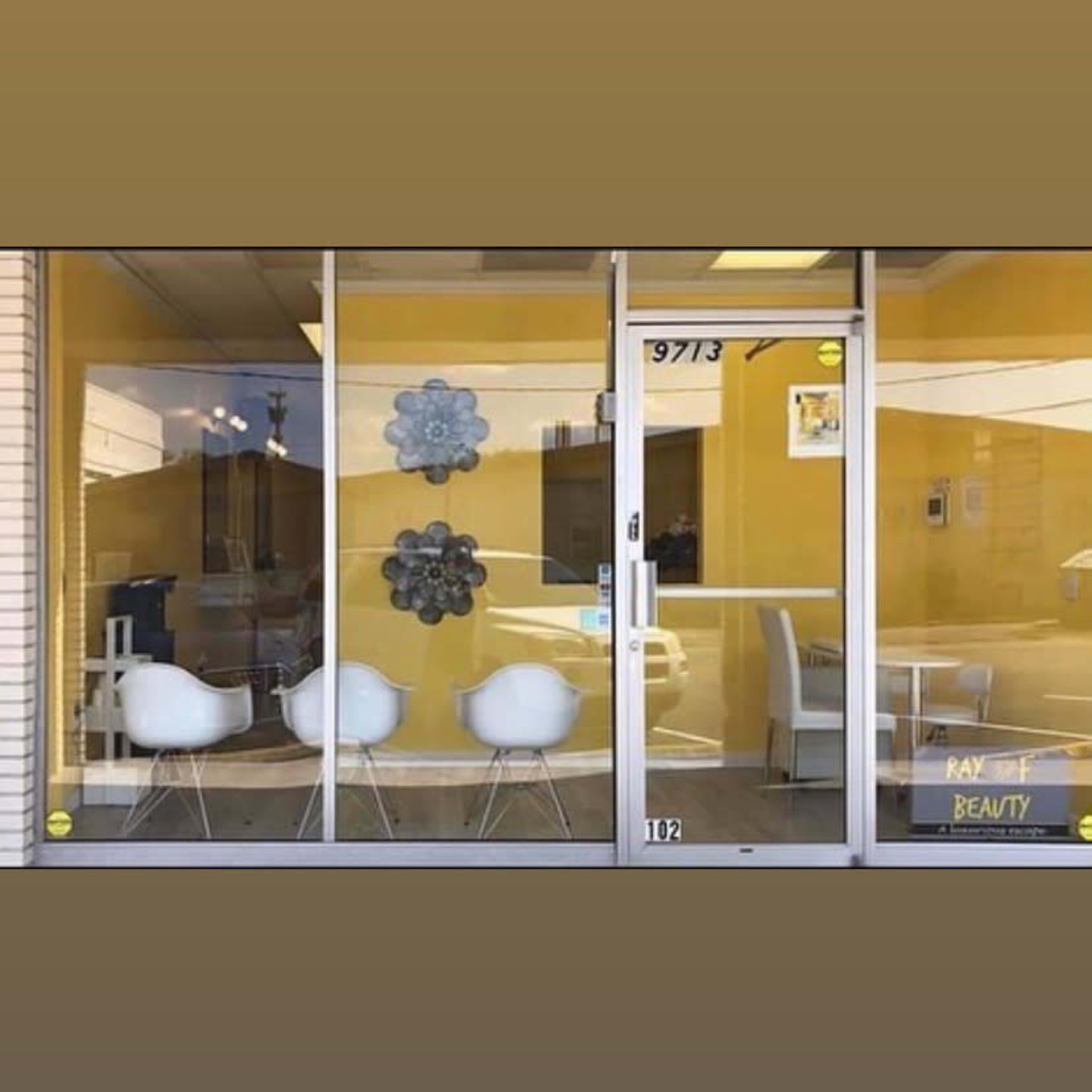 The storefront features large glass windows with three white chairs and yellow walls, displaying the name "Ray Beauty" near the entrance.