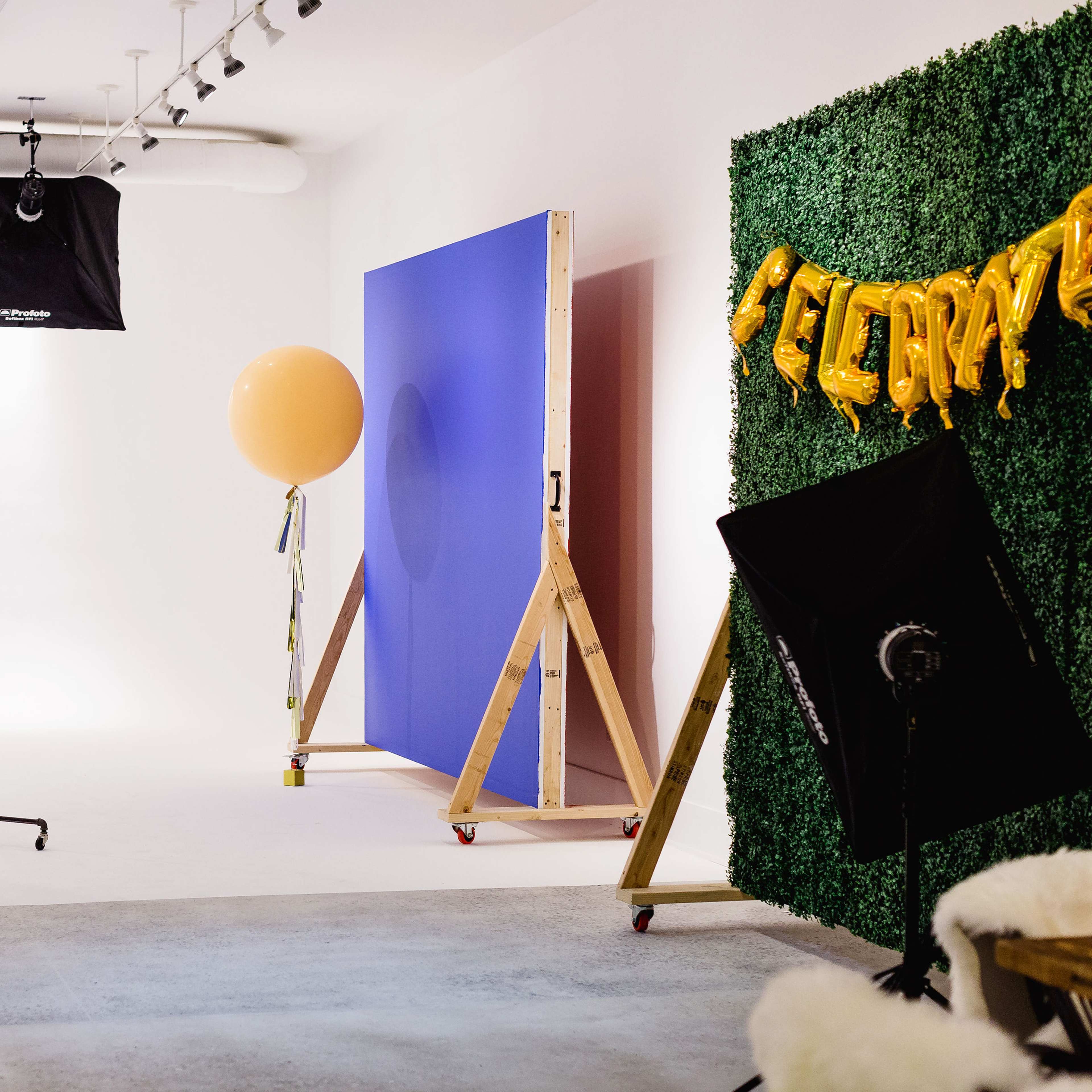 A photography studio setup with a backdrop, a clothing rack, a large balloon, and decorative elements for a celebration.