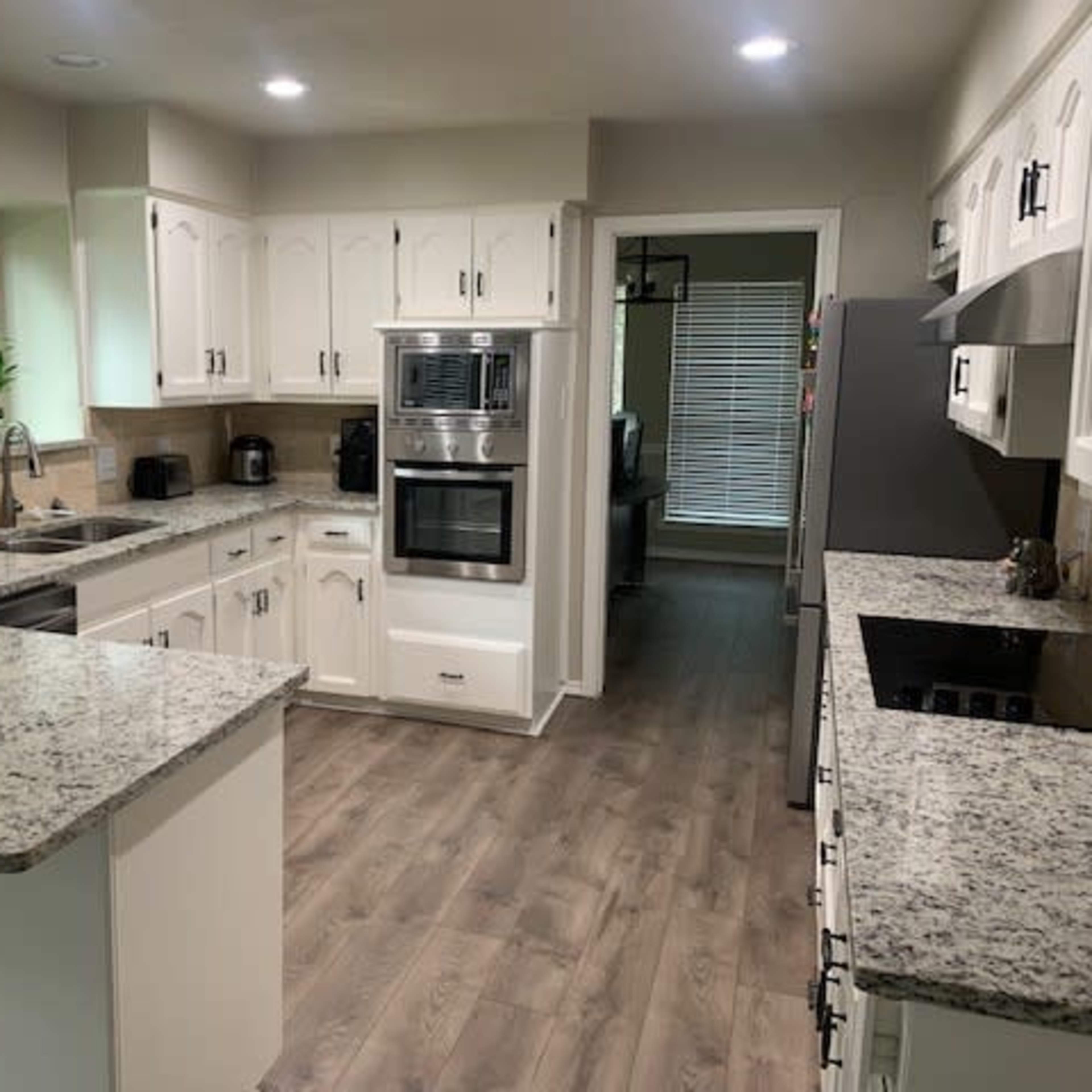 A modern kitchen features white cabinets, a granite countertop, and stainless steel appliances.