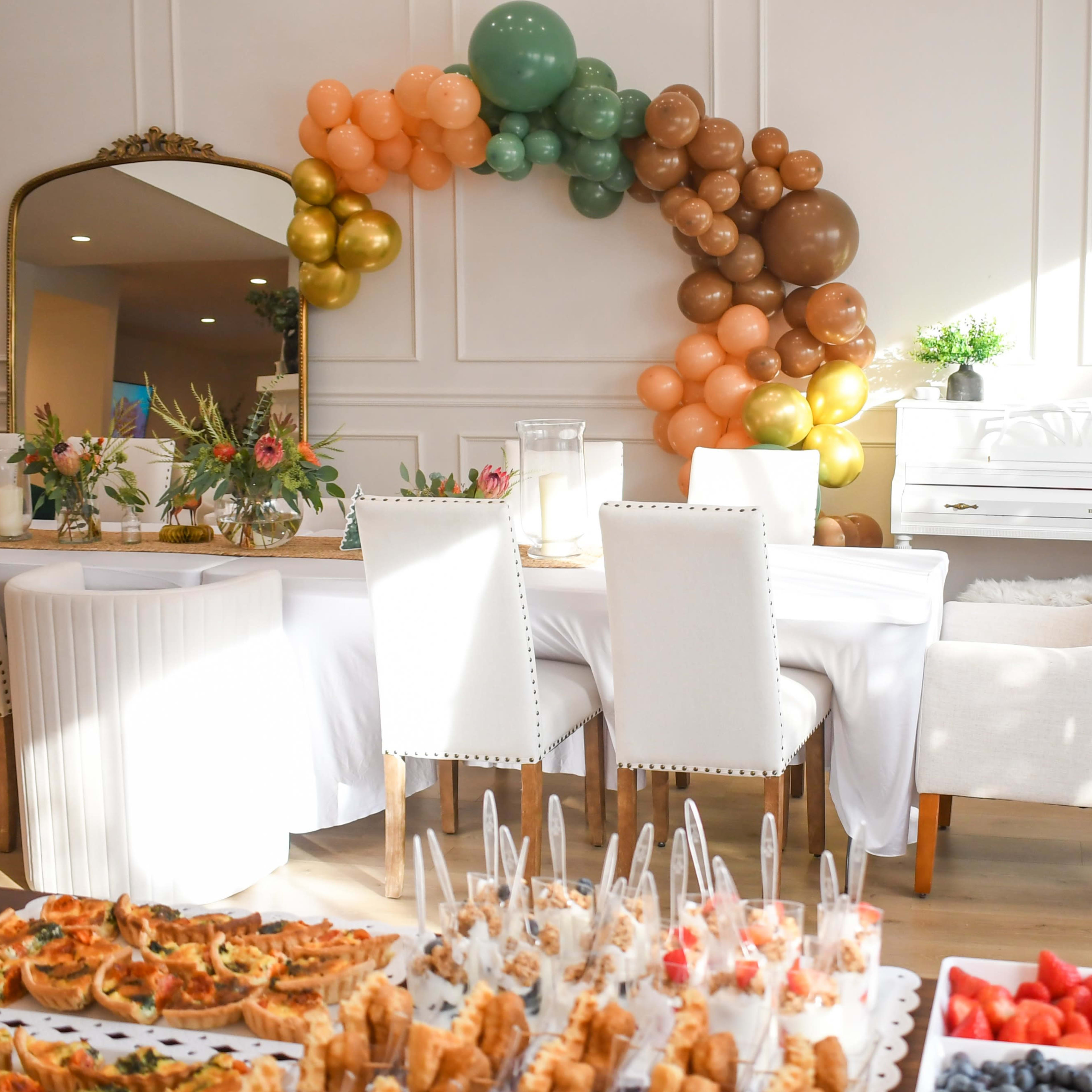 The scene features a neatly arranged dining area with a table set for a celebration, decorated with balloons and a spread of various appetizers.