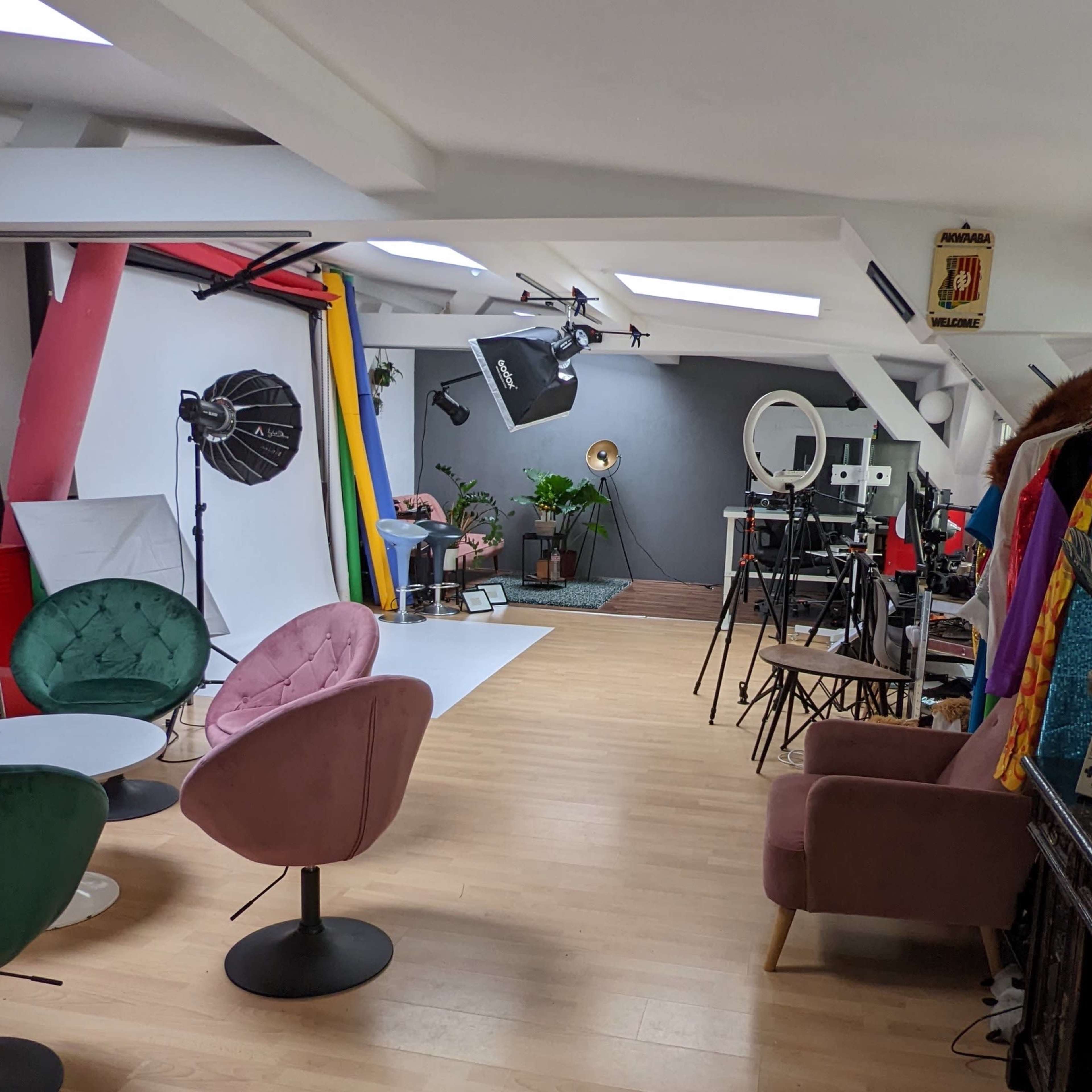 A photography studio featuring various backdrops, lighting equipment, and colorful costumes displayed on a rack.