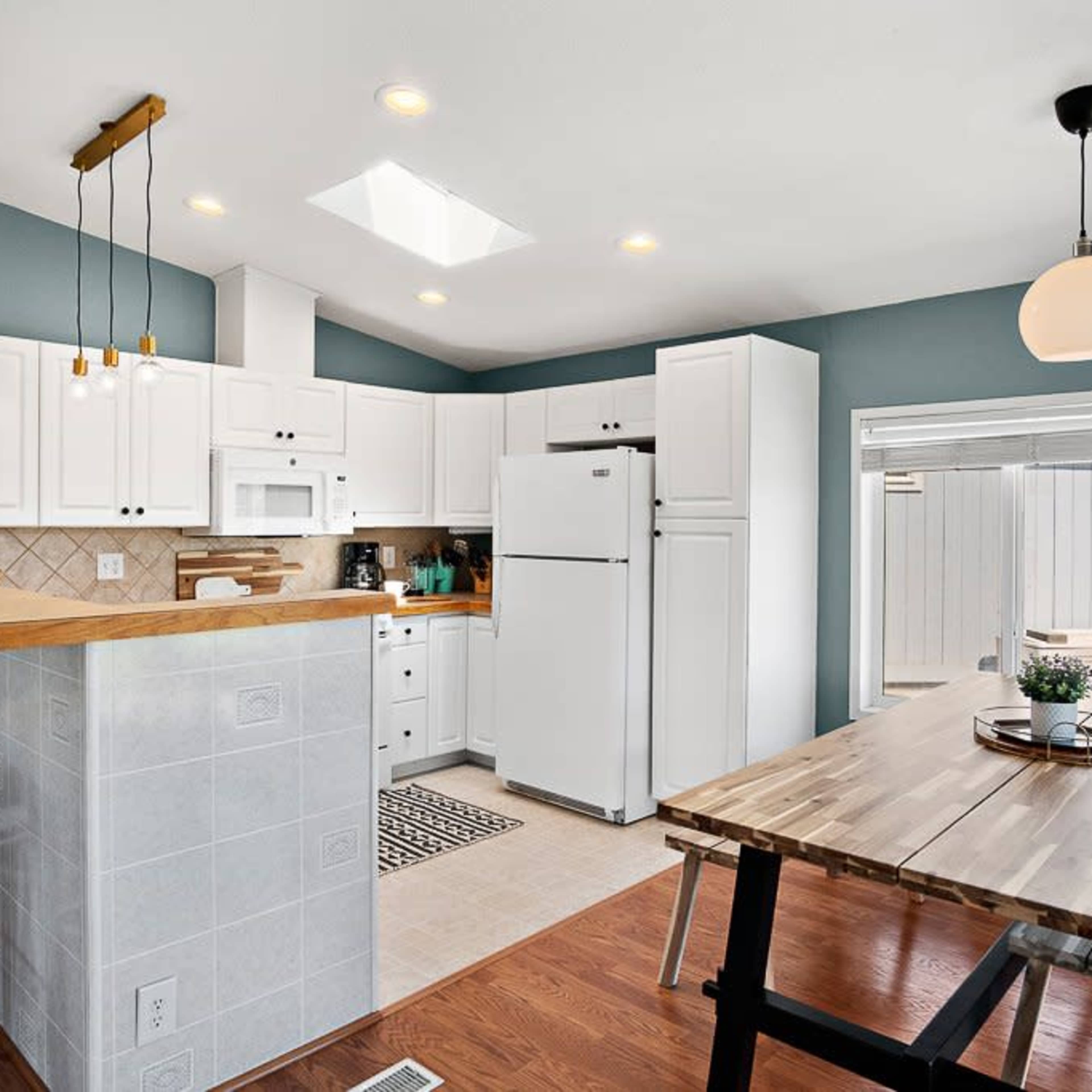 A modern kitchen with white cabinets, a central island with seating, and large windows for natural light.